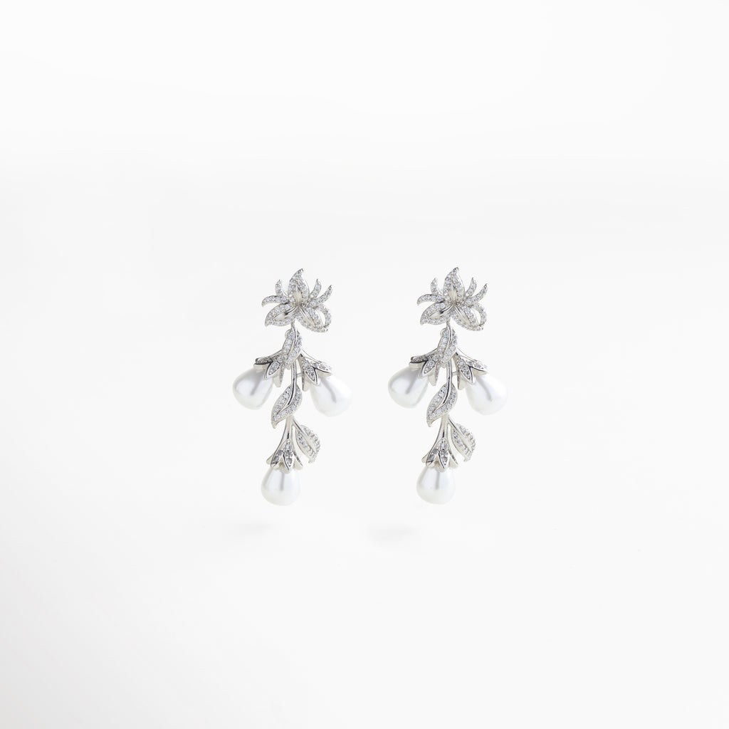 aretes plateados colgantes con diseño floral, detalles femeninos y sofisticados, incrustaciones de zirconias y perla sintética, joyería elegante para ocasiones especiales, accesorios que iluminan cualquier look