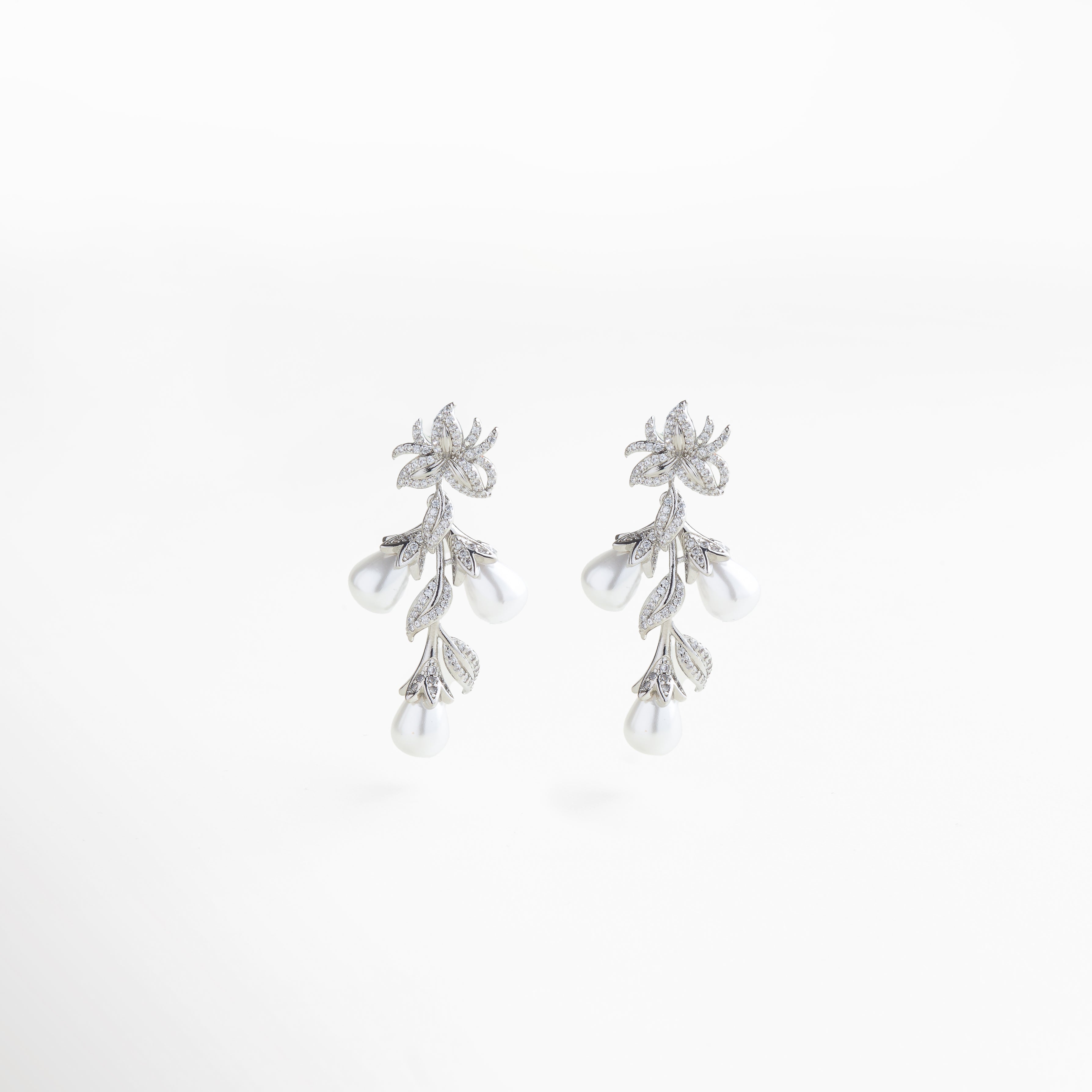 aretes plateados colgantes con diseño floral, detalles femeninos y sofisticados, incrustaciones de zirconias y perla sintética, joyería elegante para ocasiones especiales, accesorios que iluminan cualquier look