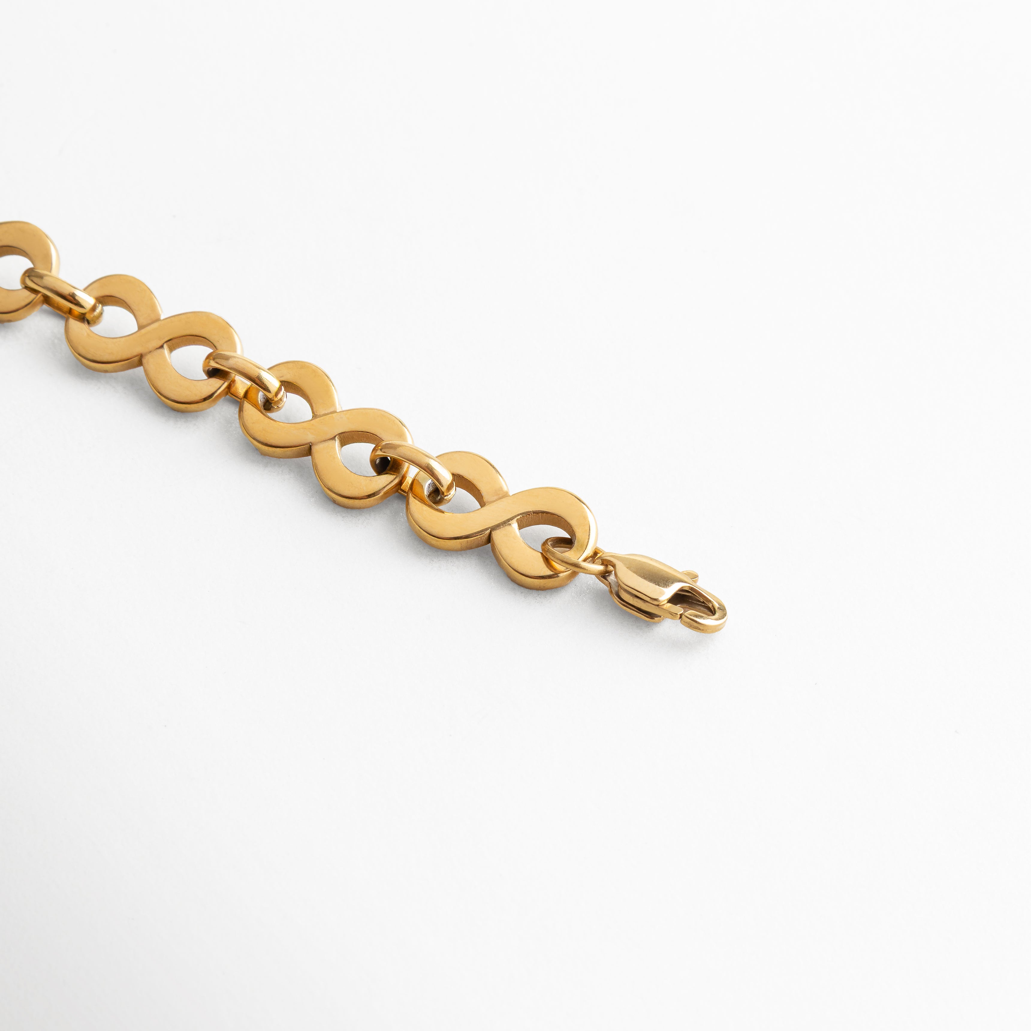 Pulsera de acero inoxidable enchapada en oro 18K, detalle del broche de cierre seguro acompañado de eslabones entrelazados, diseño moderno y atemporal que aporta fuerza y feminidad al estilo cotidiano.