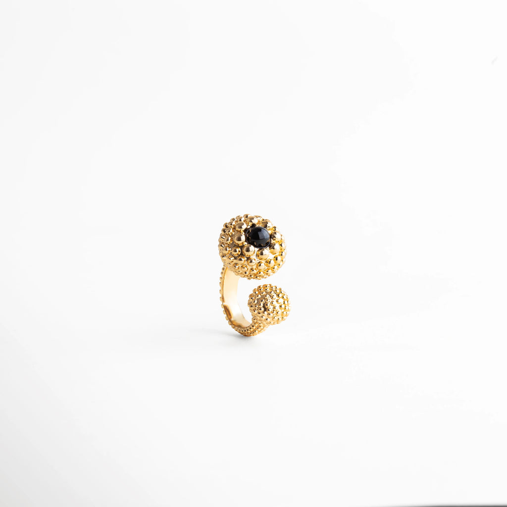 Anillo dorado con detalle texturizado y piedra negra brillante, joya elegante de diseño escultórico, perfecta para destacar con estilo y personalidad.