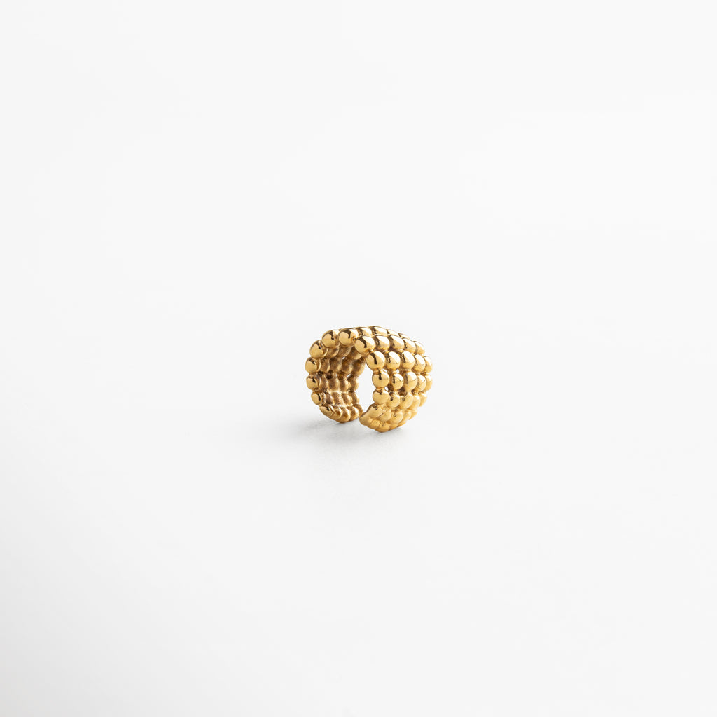 Primer plano de ear cuff macramé con diseño único, combinación de textura y brillo que aporta sofisticación y frescura, accesorio ideal para destacar con elegancia