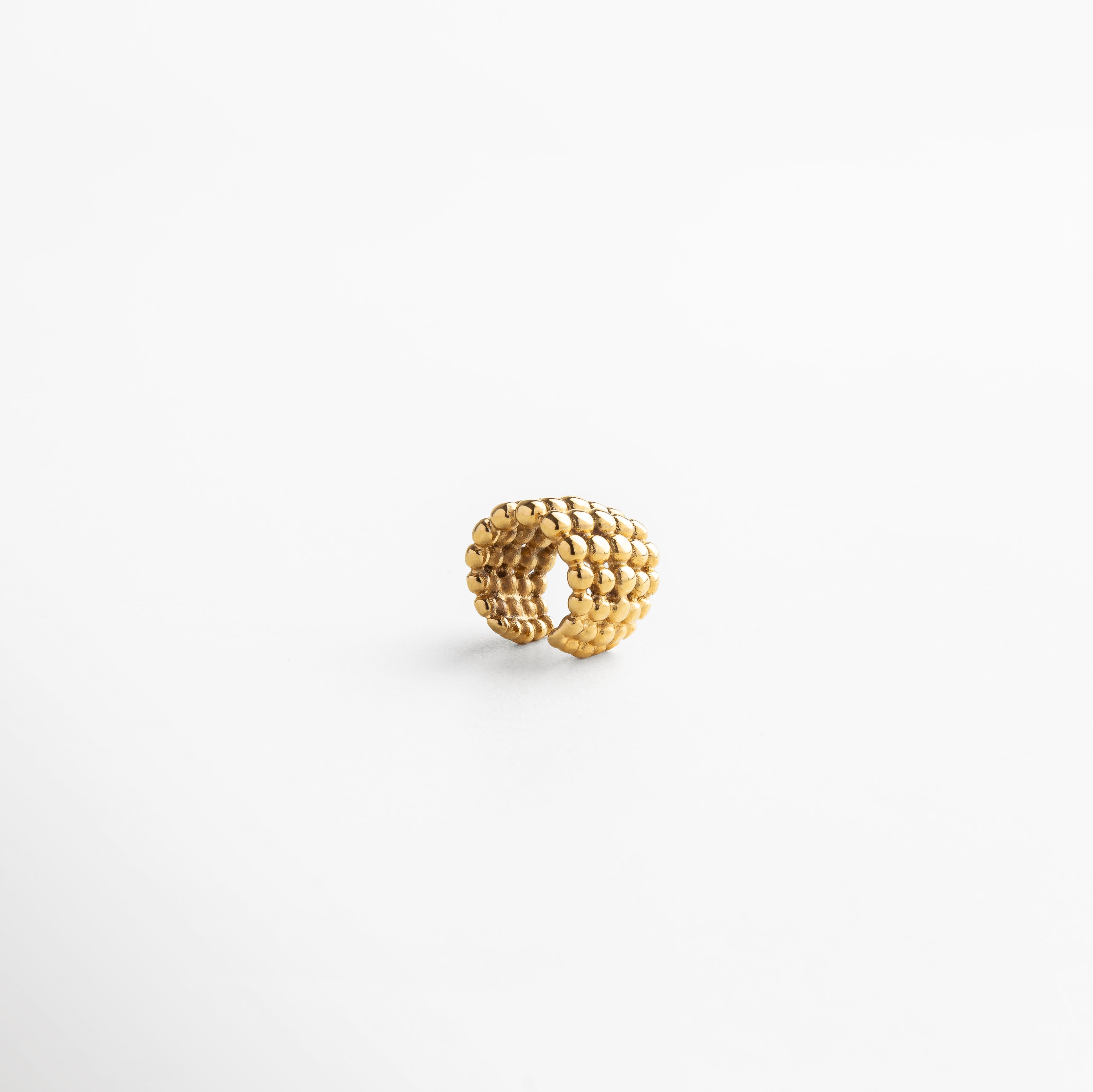 Primer plano de ear cuff macramé con diseño único, combinación de textura y brillo que aporta sofisticación y frescura, accesorio ideal para destacar con elegancia