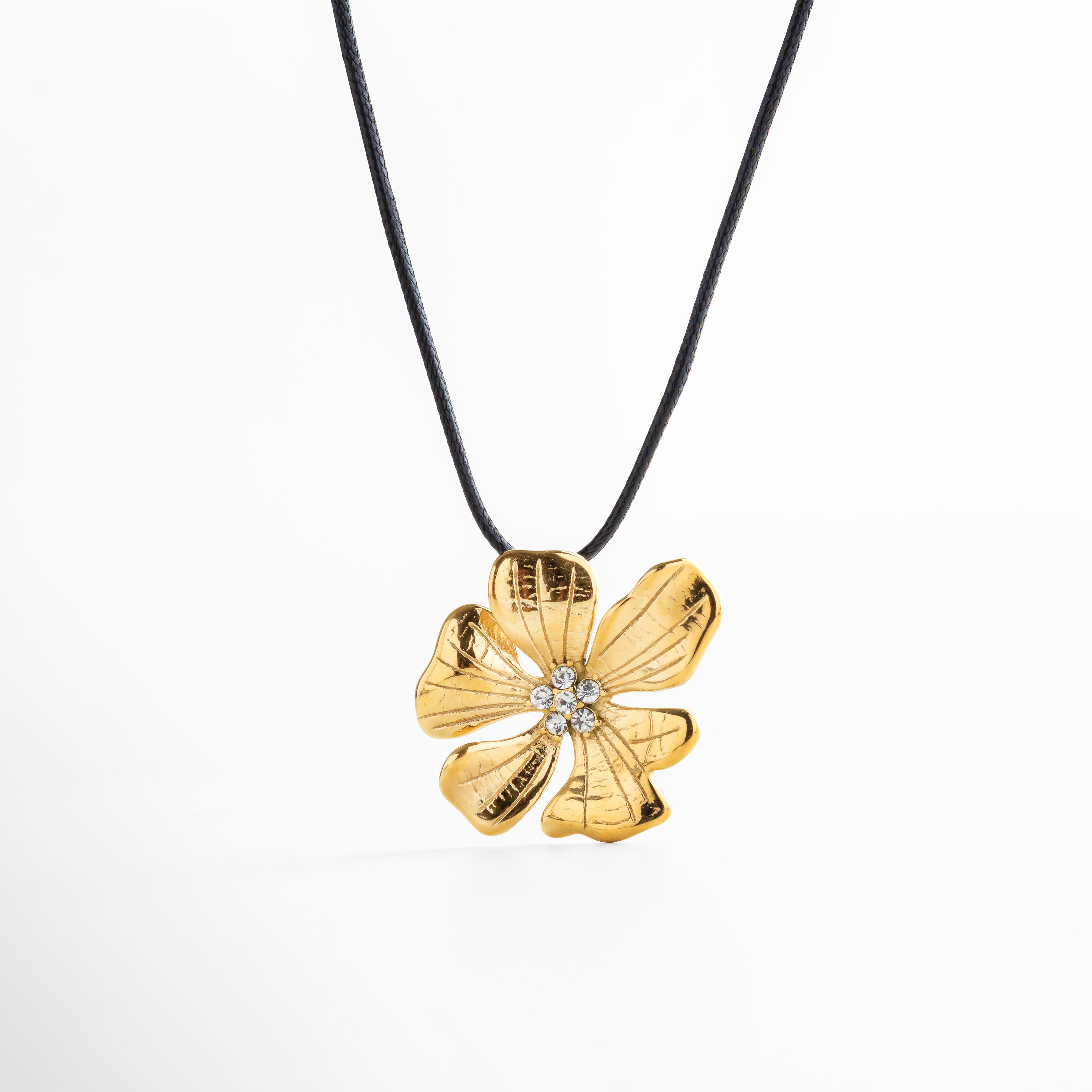 Collar con dije de flor dorada y centro decorado con zirconias, diseño elegante y moderno con cordón negro ajustable, ideal para resaltar cualquier look con un toque cálido y sofisticado