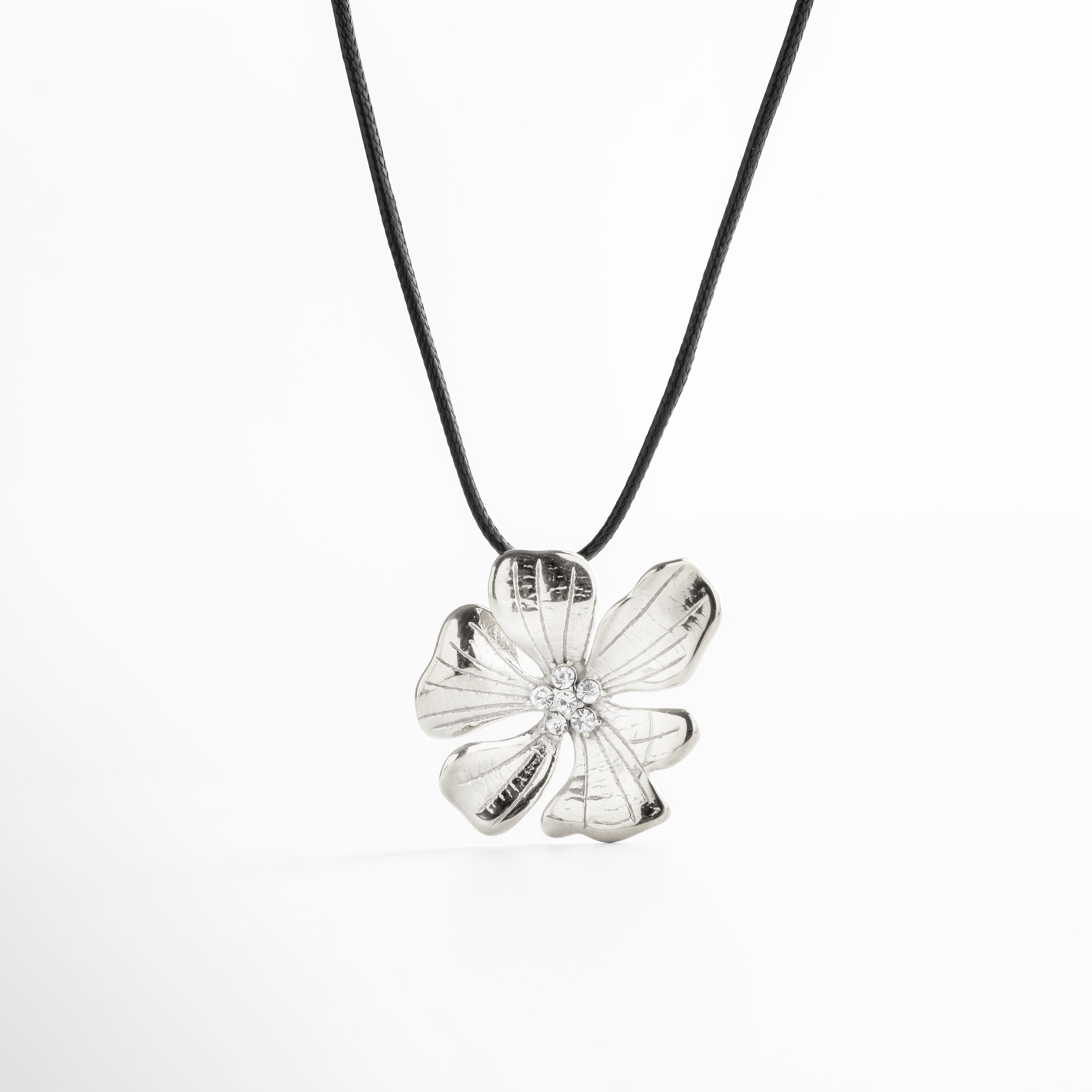 Collar con dije de flor plateada y centro con zirconias, diseño elegante y moderno con cordón negro ajustable, ideal para destacar con un toque delicado y brillante