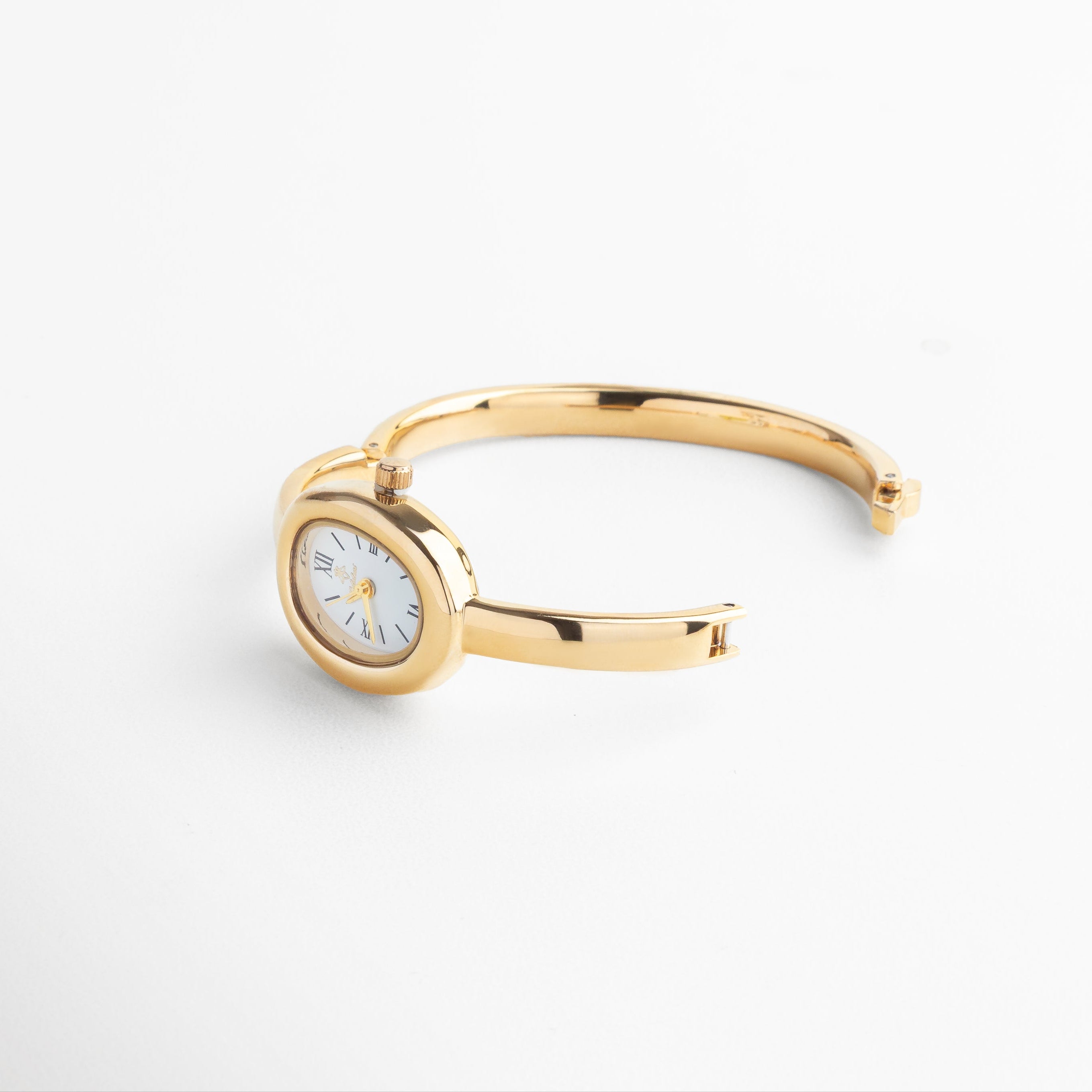 Vista superior del Reloj Braccialetto dorado, mostrando su diámetro de 6 cm y caja central de 2 cm. Toma cenital del reloj tipo brazalete dorado, con diseño curvo y estilizado en acero inoxidable con chapa de oro. Perspectiva superior del Reloj Braccialetto, resaltando su diseño limpio, minimalista y femenino. Reloj dorado visto desde arriba, con brazalete rígido de 0.3 cm de ancho y esfera delicada. Vista desde arriba del Reloj Braccialetto, con diseño cerrado tipo brazalete y acabado metál