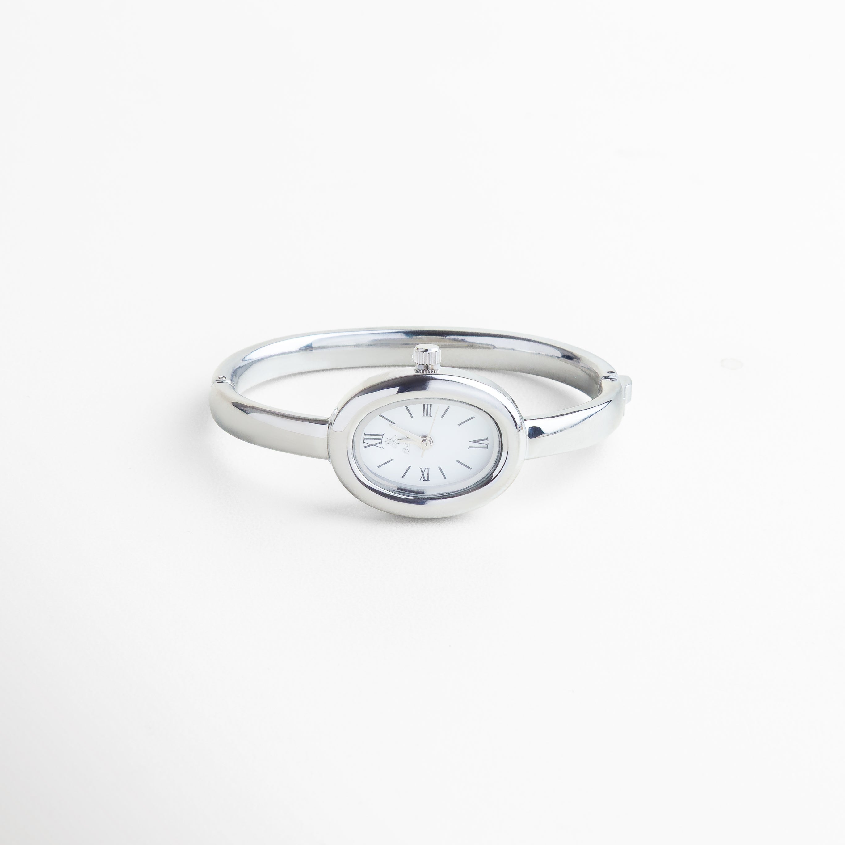 Vista superior del Reloj Braccialetto plateado, mostrando su diámetro de 6 cm y diseño limpio en forma de pulsera. Toma cenital del reloj tipo brazalete en acero plateado, con vitrina de 2 cm y cuerpo estilizado. Reloj Braccialetto visto desde arriba, con diseño metálico brillante y estructura delgada de 0.3 cm. Perspectiva superior del reloj rígido plateado, con líneas curvas y diseño minimalista. Vista desde arriba del Reloj Braccialetto en acero inoxidable, destacando su forma de brazalet