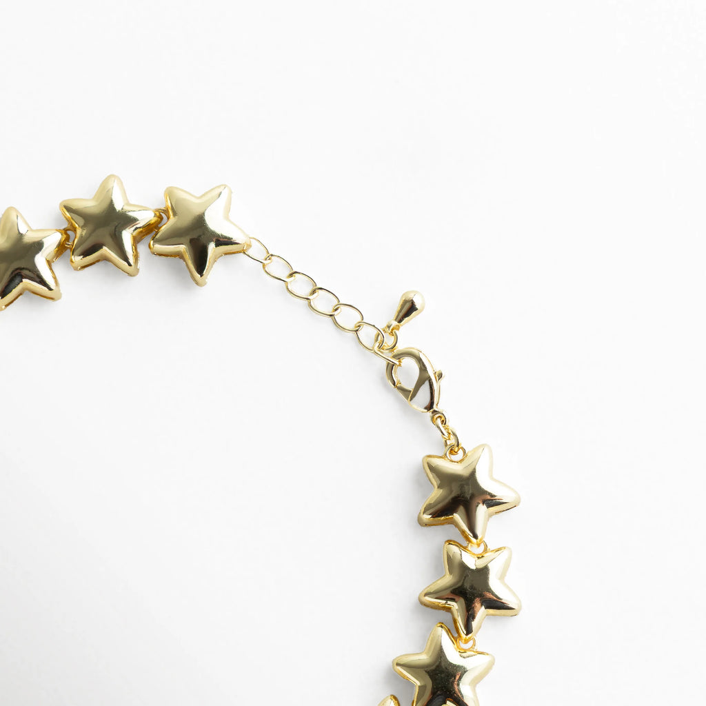 Detalle del broche de la pulsera con extensión ajustable, mostrando el acabado dorado brillante y la continuidad perfecta de las estrellas. El cierre tipo mosquetón combina funcionalidad y estilo, manteniendo el toque moderno y femenino del diseño.