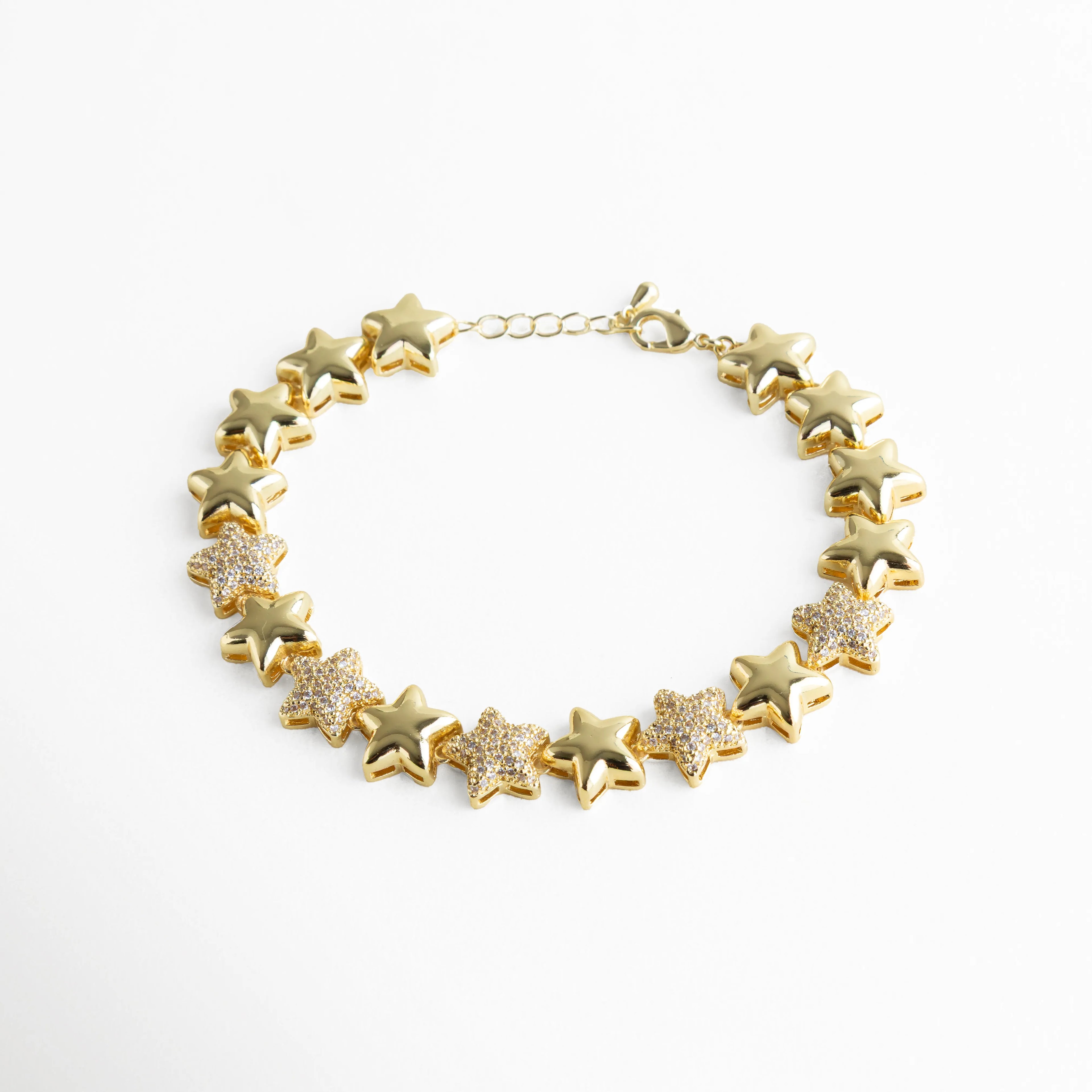 Pulsera dorada compuesta por estrellas en relieve, intercaladas con zirconias que aportan un brillo sutil y sofisticado. Su estructura articulada permite que se adapte con suavidad a la muñeca, ideal para elevar cualquier look con un toque de luz y delicadeza.
