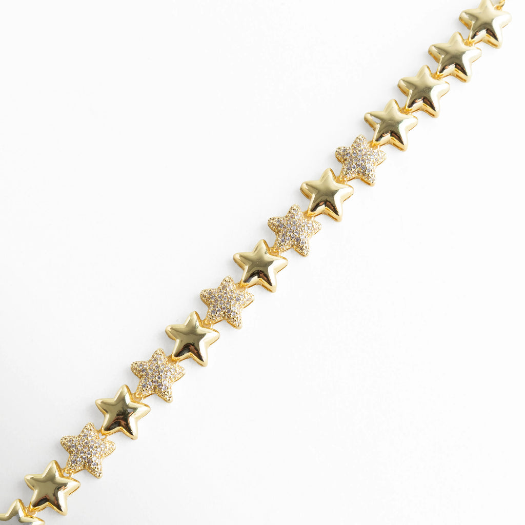 Pulsera dorada con motivo estelar, vista en detalle para resaltar la armonía entre las estrellas lisas y las pavonadas en zirconias. La imagen refleja la inspiración cósmica de la pieza, perfecta para quienes buscan joyas con un aire romántico y contemporáneo.