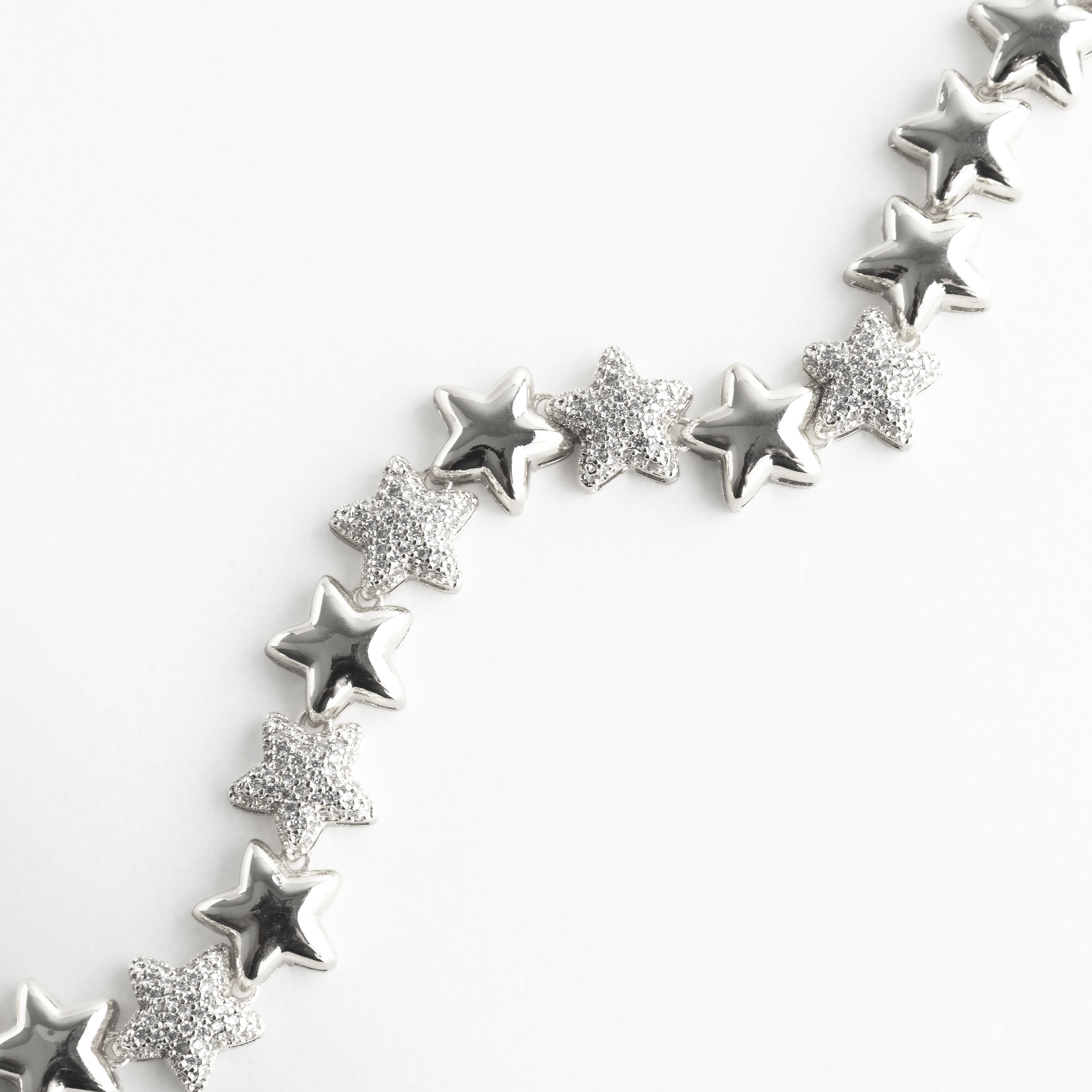 Pulsera plateada con motivo estelar, vista en detalle para resaltar la armonía entre las estrellas lisas y las pavonadas en zirconias. La imagen refleja la inspiración cósmica de la pieza, perfecta para quienes buscan joyas con un aire romántico y contemporáneo.
