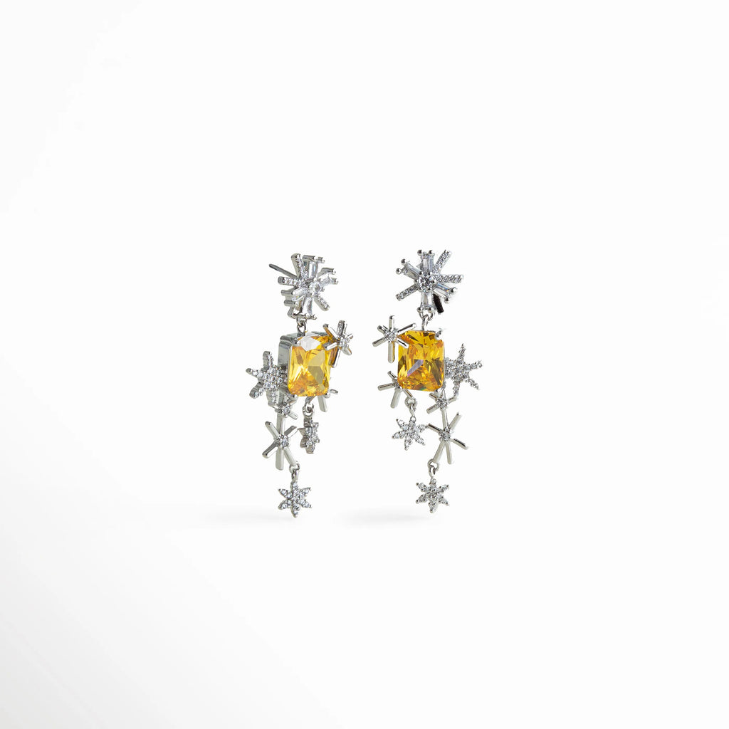 Aretes colgantes con estrella plateada y piedra cúbica amarilla, diseño inspirado en constelaciones que aporta un toque audaz y luminoso.