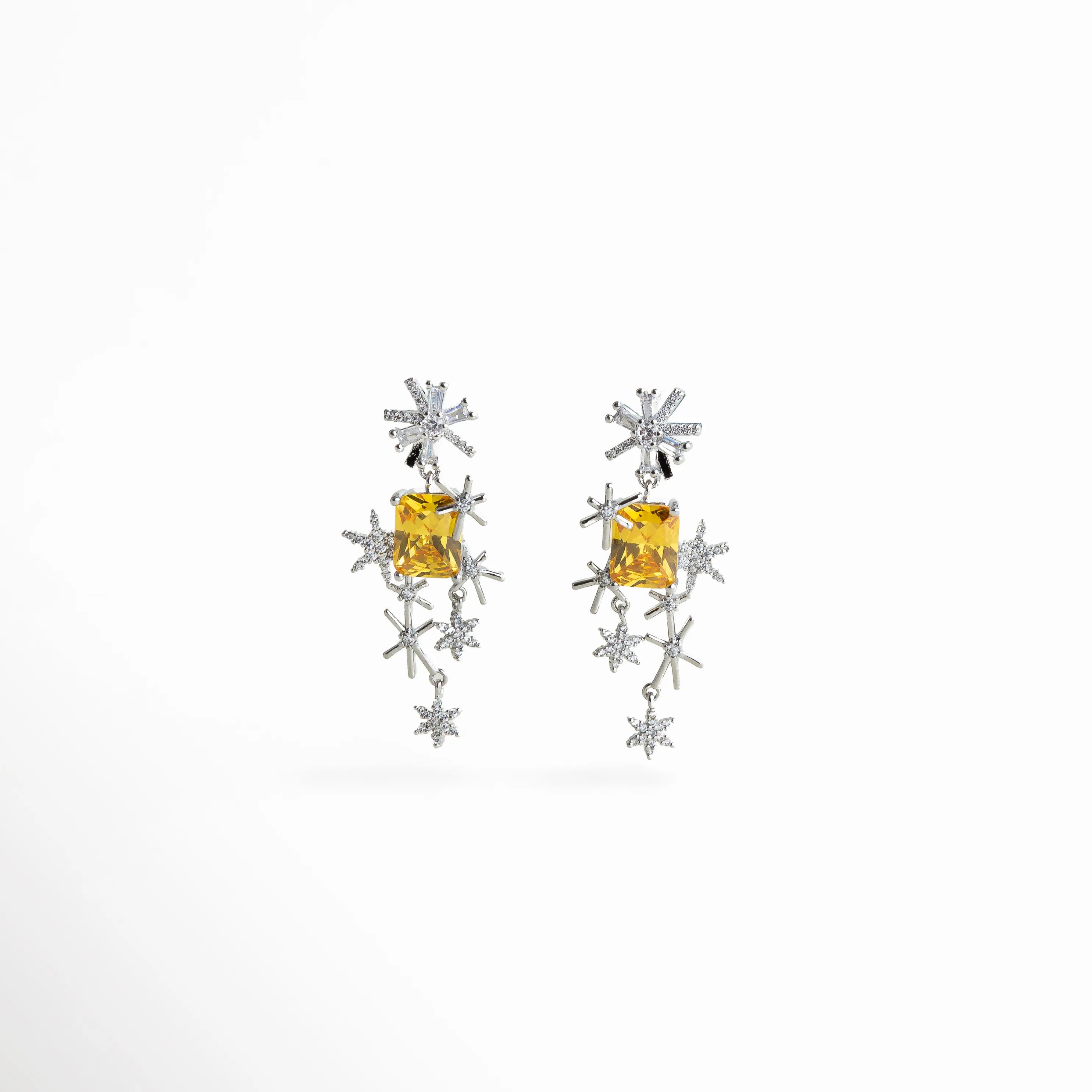 Aretes plateados con zirconias en forma de estrella y piedra central amarilla, diseño moderno que combina brillo y color para un look elegante.