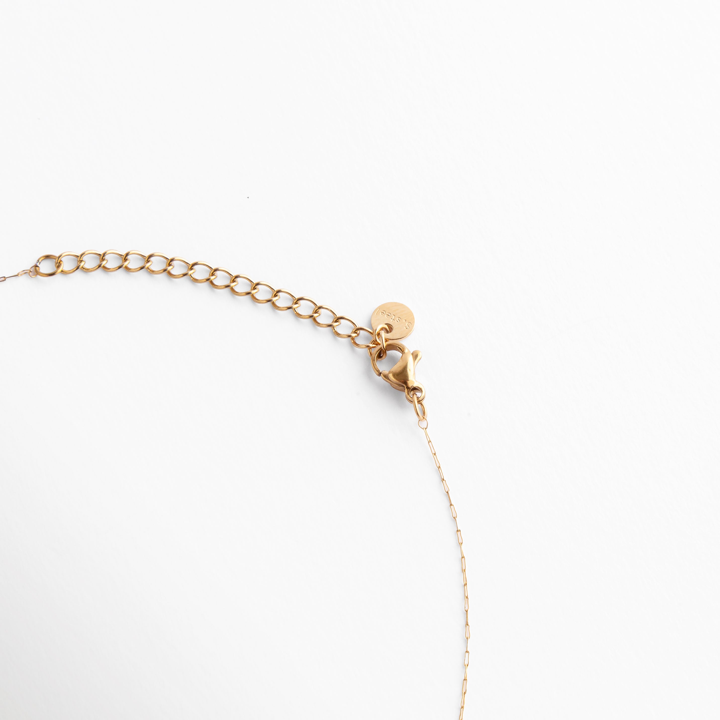 Detalle del broche ajustable en tono dorado con cadena fina, diseño versátil y sofisticado que complementa cualquier look.