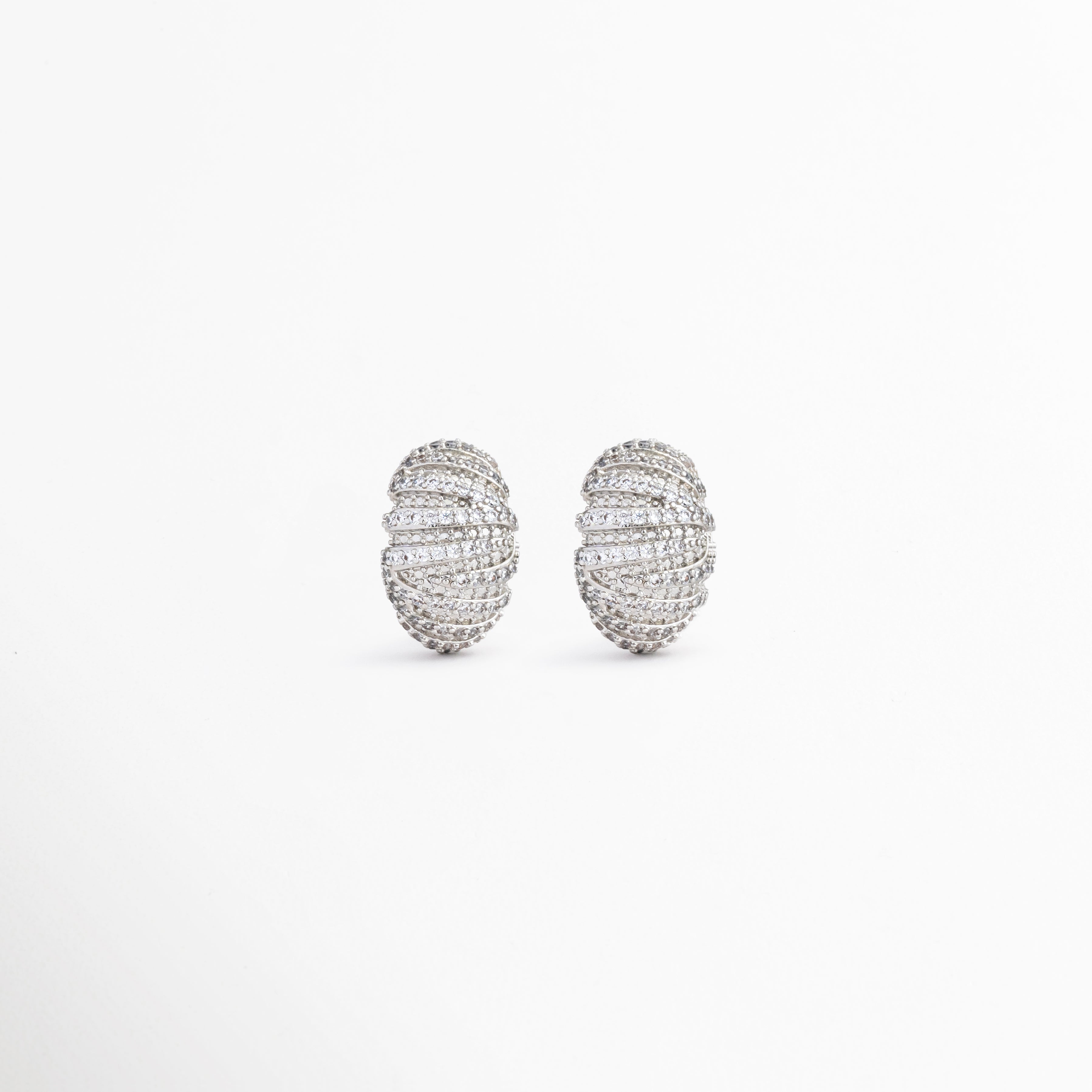 Aretes Silver Mila con zirconias y acabado en oro blanco 18K, Pendientes ovalados plateados con diseño elegante y brillante, Aretes Silver Mila con textura acanalada y zirconias, Aretes sofisticados con acabado brillante y detalles de zirconia, Pendientes plateados de estilo atemporal para cualquier ocasión.