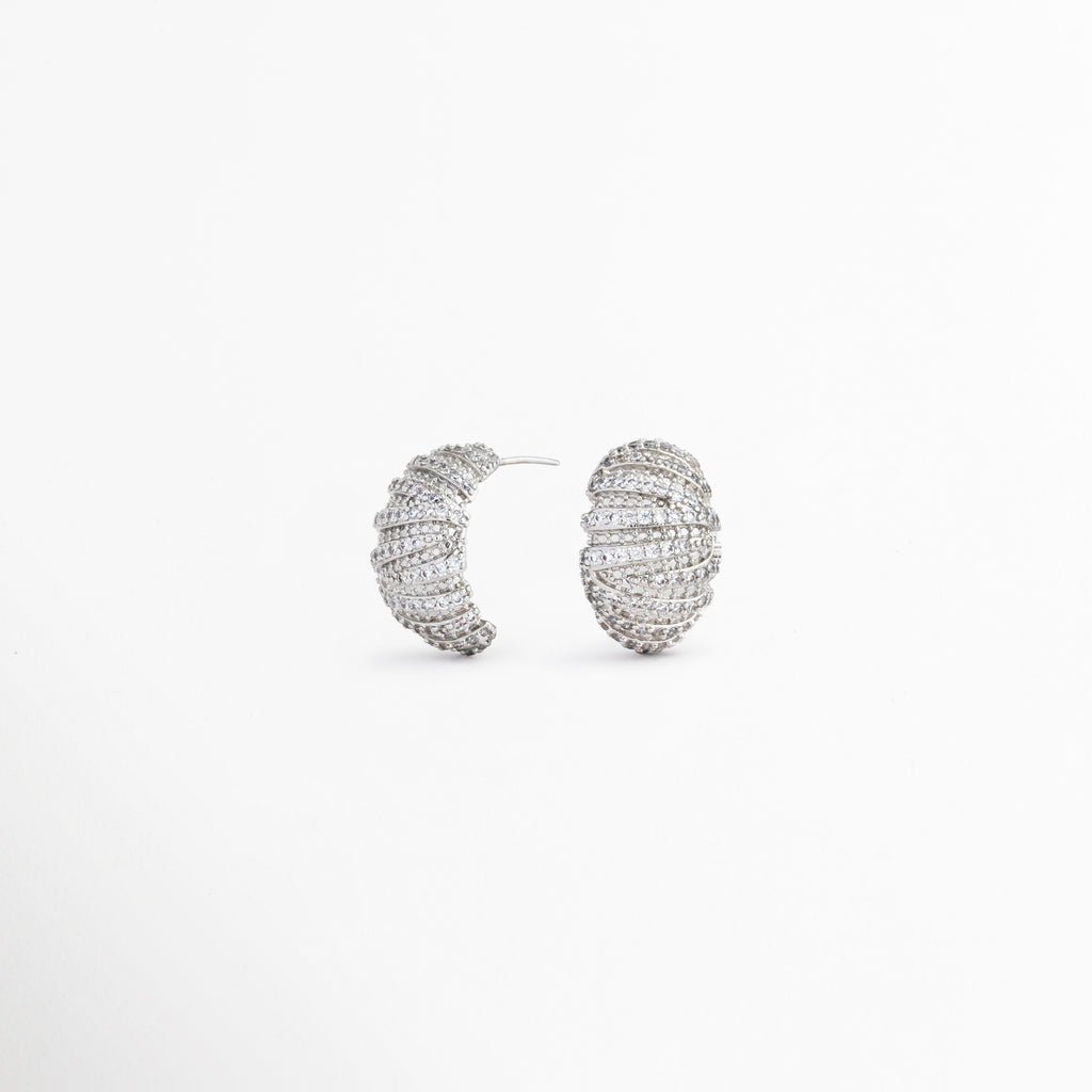 Vista lateral de aretes Silver Mila con zirconias, Perfil de pendientes ovalados con acabado en oro blanco 18K, Detalle lateral de aretes elegantes con textura acanalada, Aretes plateados con diseño ligero y sofisticado, Vista lateral de pendientes con brillo de zirconias.