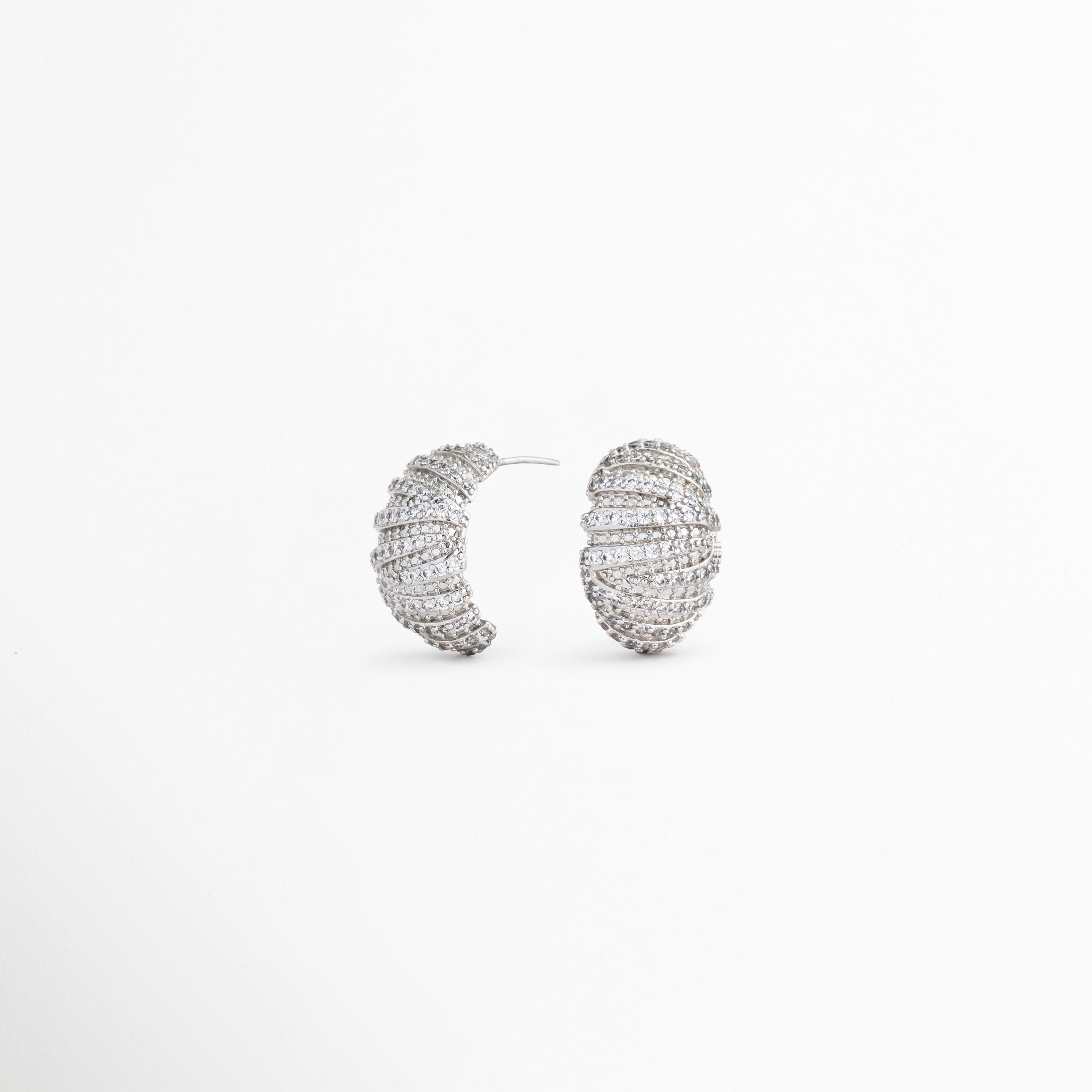 Vista lateral de aretes Silver Mila con zirconias, Perfil de pendientes ovalados con acabado en oro blanco 18K, Detalle lateral de aretes elegantes con textura acanalada, Aretes plateados con diseño ligero y sofisticado, Vista lateral de pendientes con brillo de zirconias.
