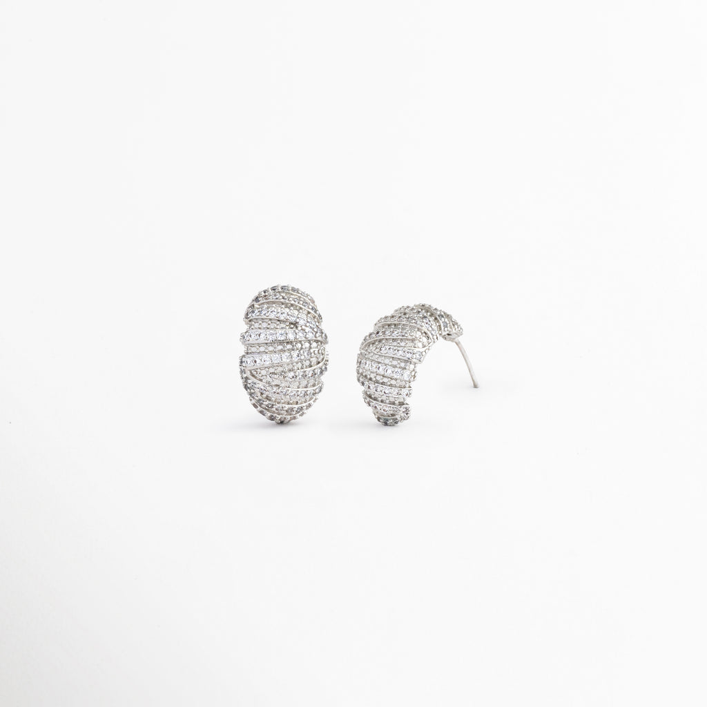 Vista inclinada de aretes Silver Mila con acabado brillante, Pendientes ovalados con zirconias y diseño contemporáneo, Detalle de aretes plateados con textura y brillo sutil, Aretes elegantes para mujer con incrustaciones de zirconia, Vista complementaria de pendientes Silver Mila con acabado premium.