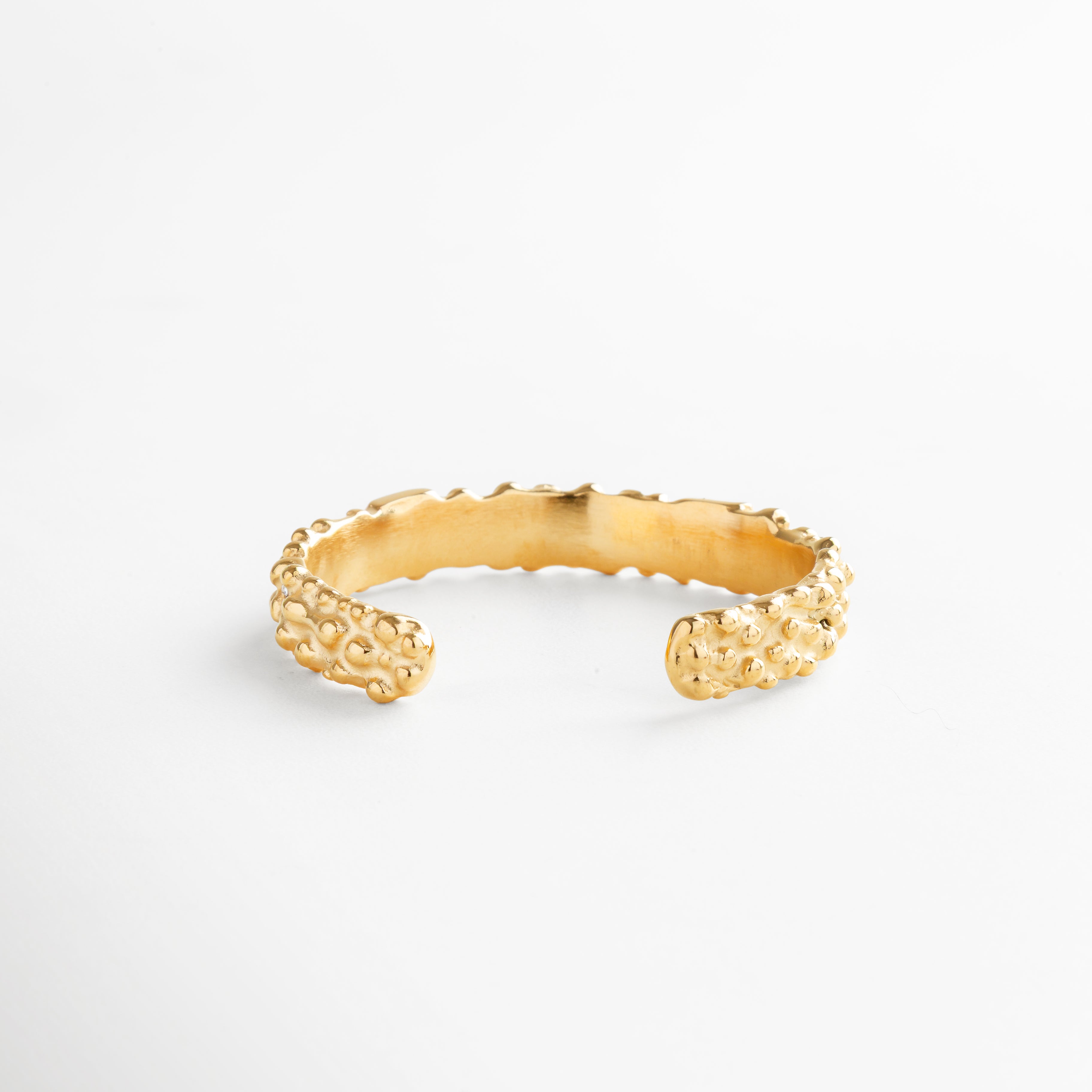 Pulsera abierta dorada con acabado martillado y textura orgánica, diseño minimalista en acero inoxidable con baño en oro 18K, pieza versátil y moderna sin cierres.