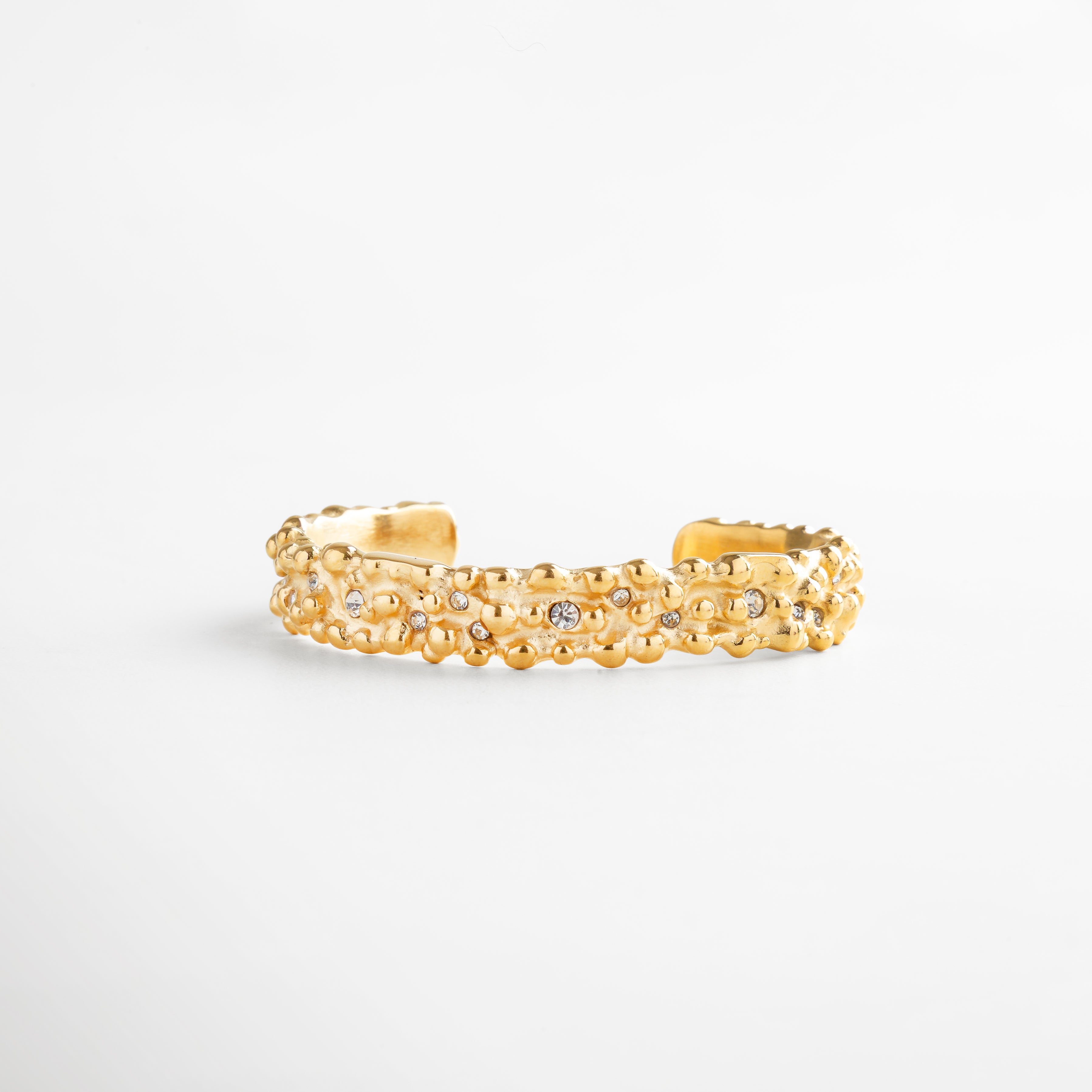 Pulsera rígida dorada con incrustaciones de zirconias, detalle texturizado en oro 18K, accesorio de lujo atemporal para realzar cualquier outfit con elegancia.