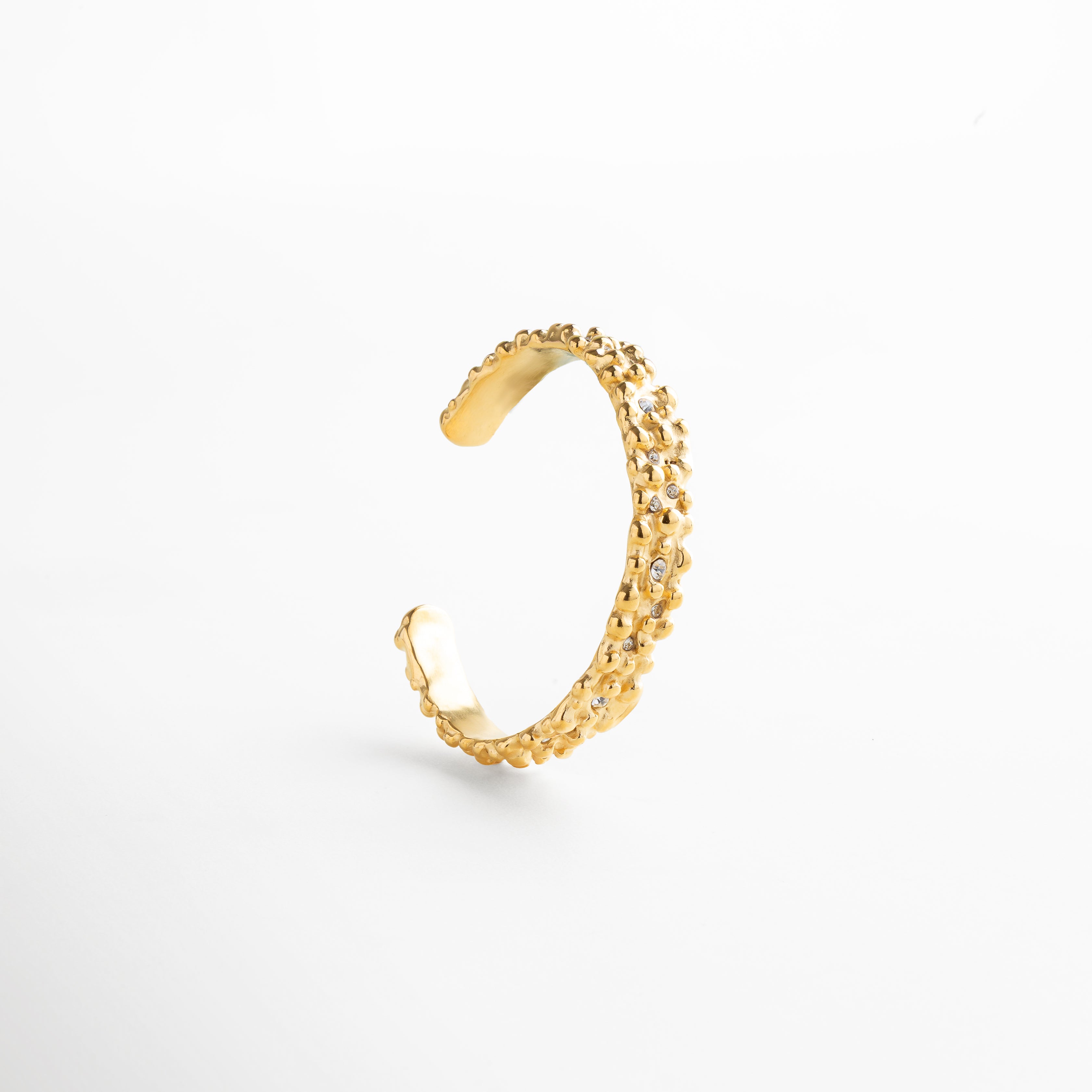 Pulsera dorada con zirconias incrustadas en textura burbuja, joya rígida en oro 18K, diseño elegante y sofisticado que refleja destellos de luz únicos.
