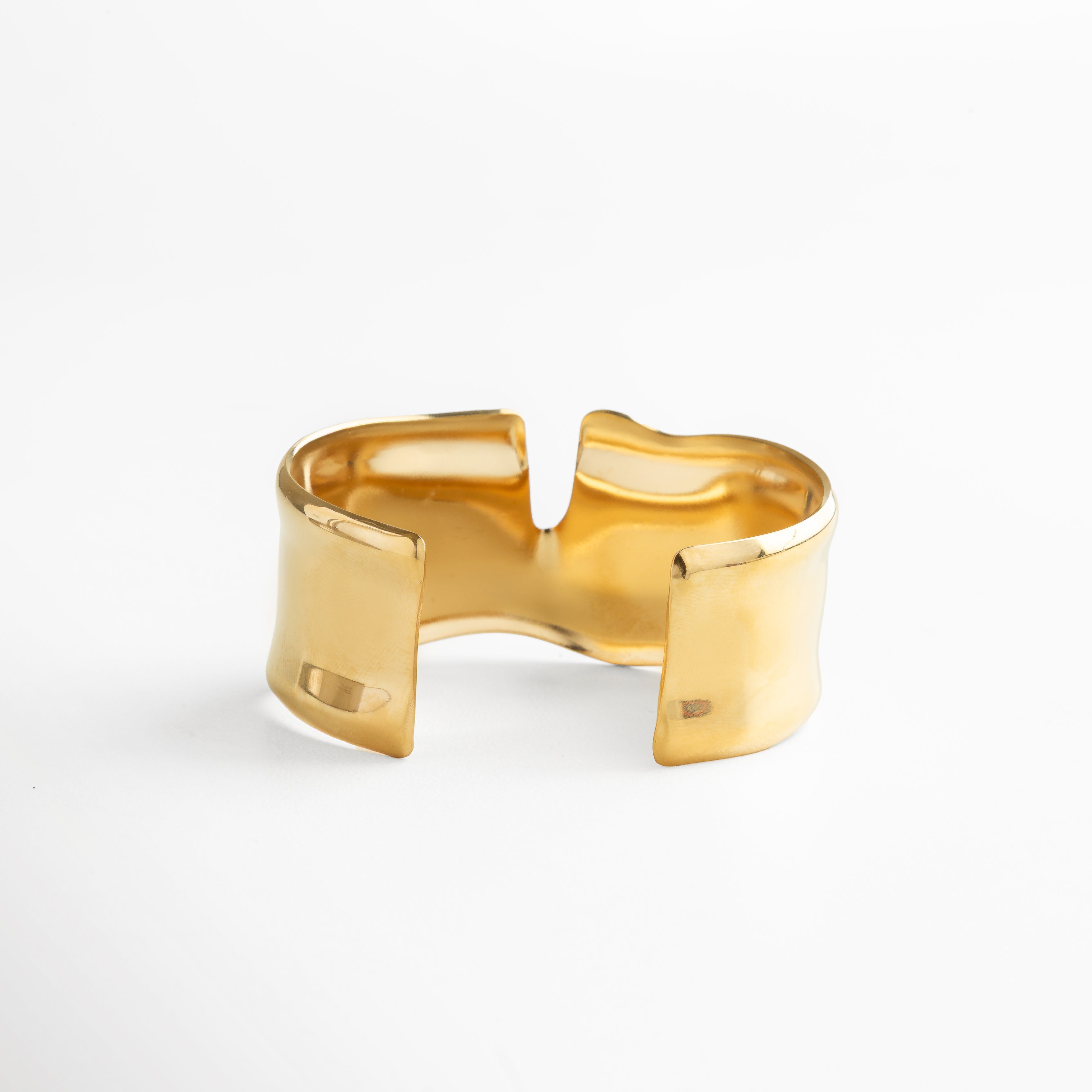 Pulsera abierta dorada con diseño ajustable, acabado pulido en oro 18K, joya bold y contemporánea que combina minimalismo con sofisticación.
