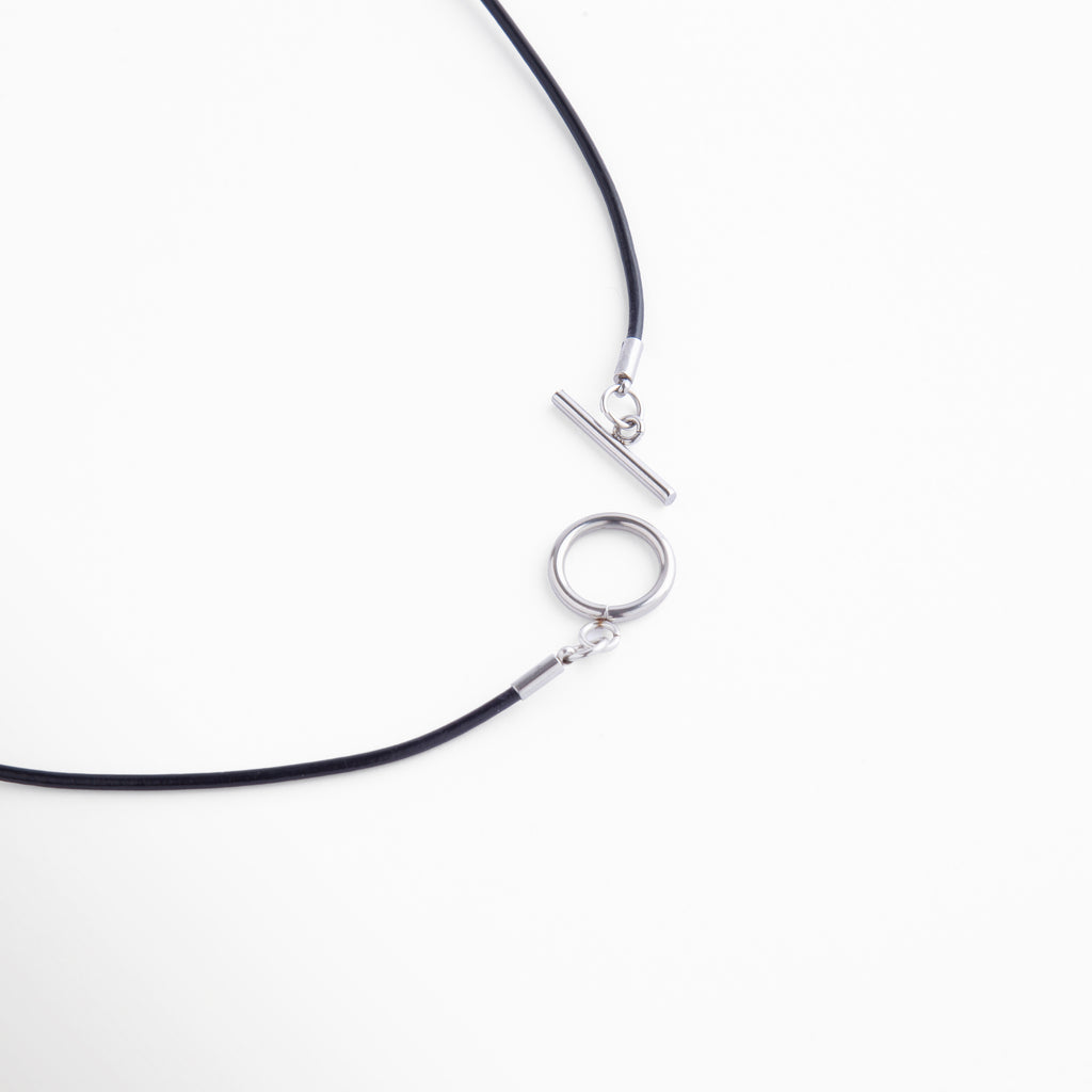 Detalle del cierre tipo barra en acero plateado con diseño circular, fácil de usar y elegante, que complementa el estilo sofisticado del collar.