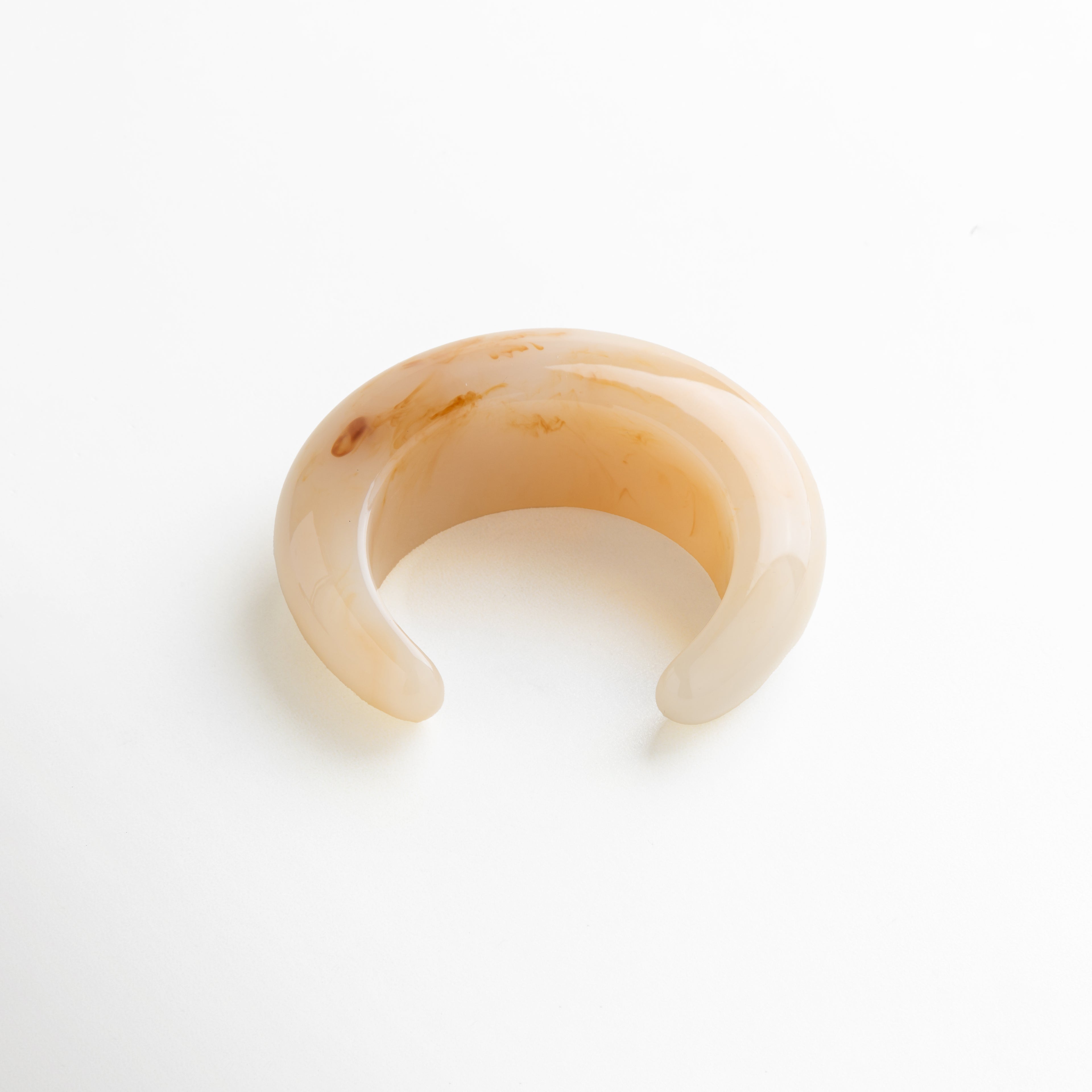 Pulsera abierta de resina en tono neutro con textura natural, diseño elegante y voluminoso, accesorio atemporal de inspiración orgánica.
