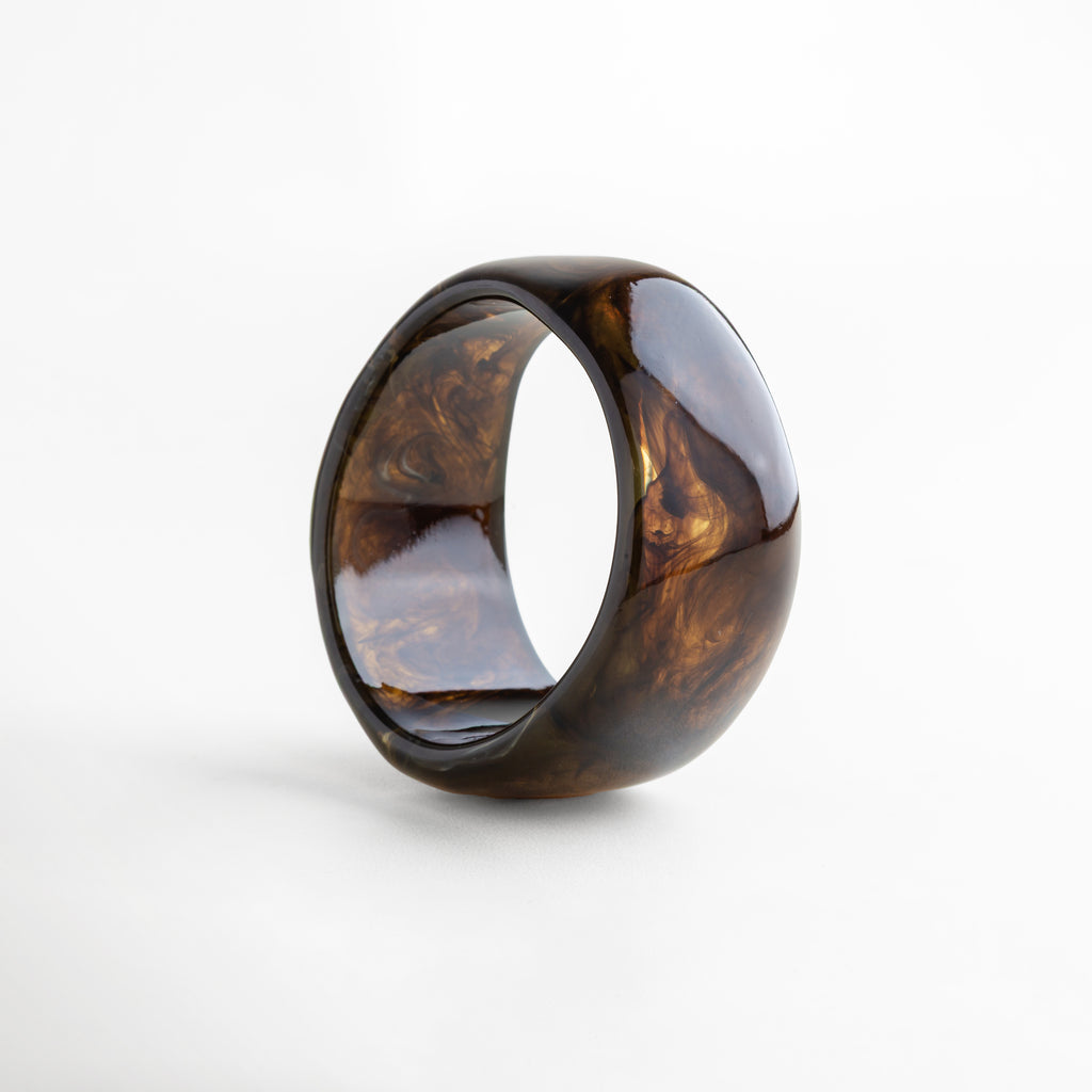 Pulsera bold de resina en tono ámbar brillante con acabado marmoleado, pieza moderna y llamativa que realza cualquier outfit.