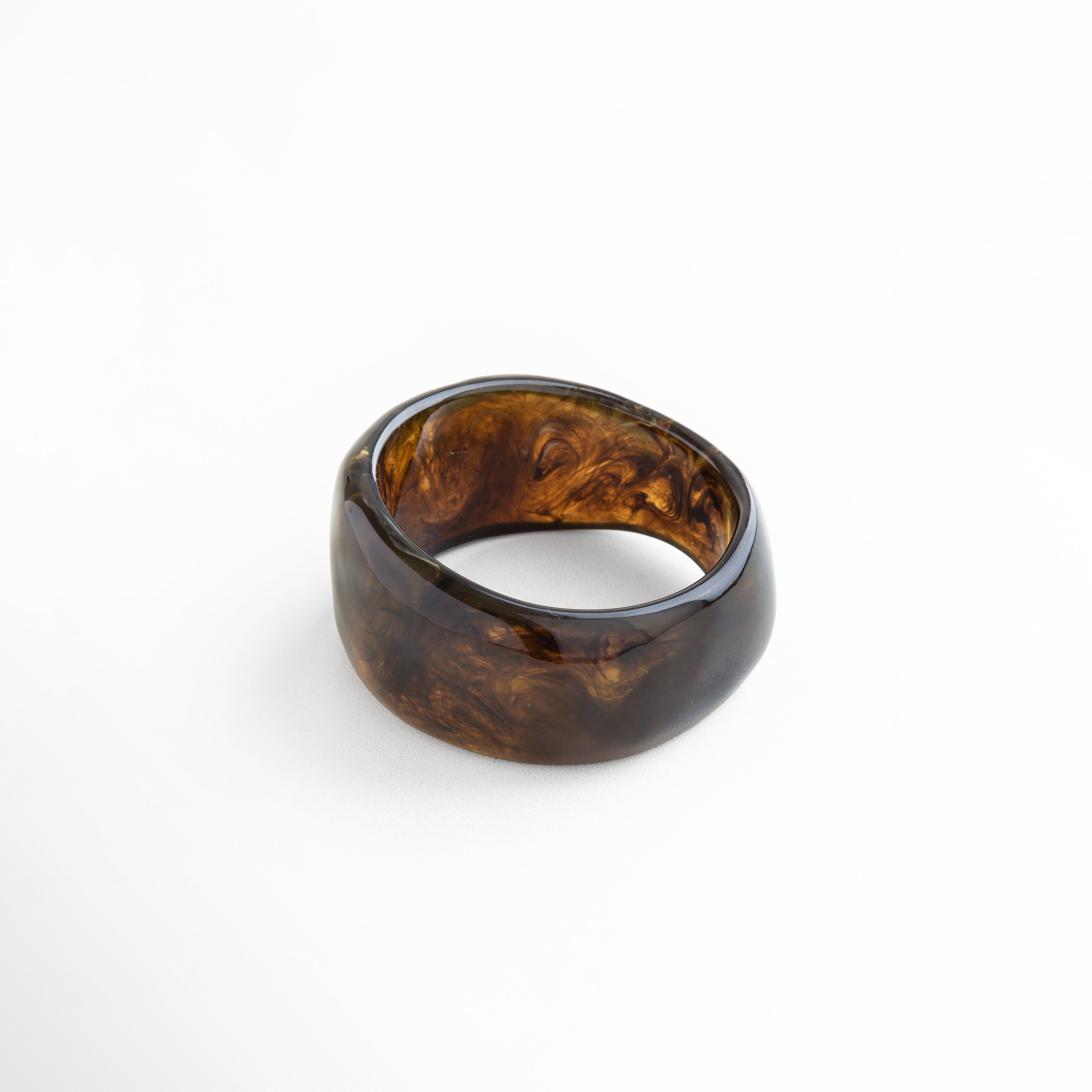 Pulsera de resina marrón con vetas marmoleadas y acabado brillante, pieza bold contemporánea que transmite autenticidad y fuerza.