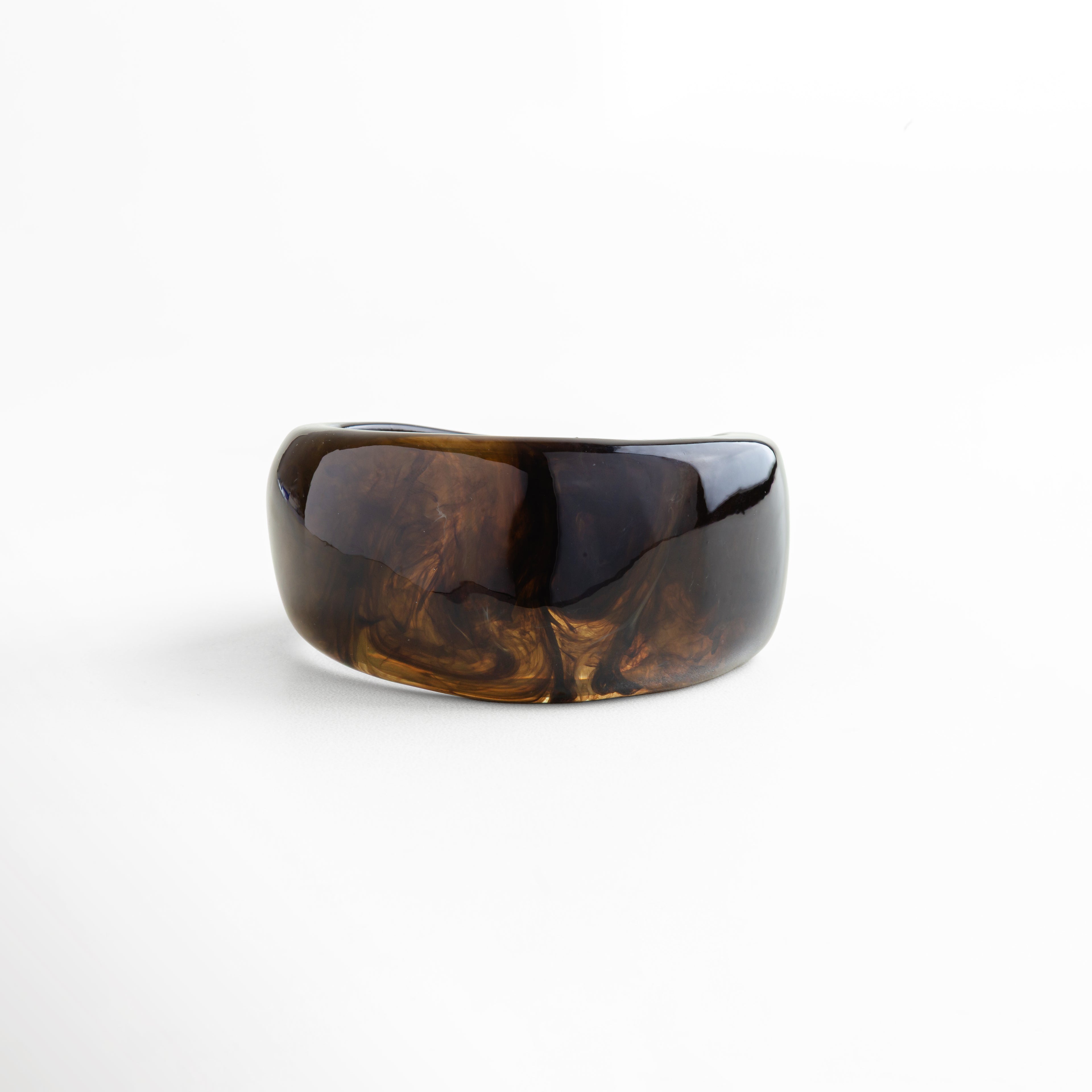 Pulsera ancha de resina en tono ámbar oscuro con acabado marmoleado brillante, diseño bold y sofisticado, ideal para un estilo moderno y distintivo.