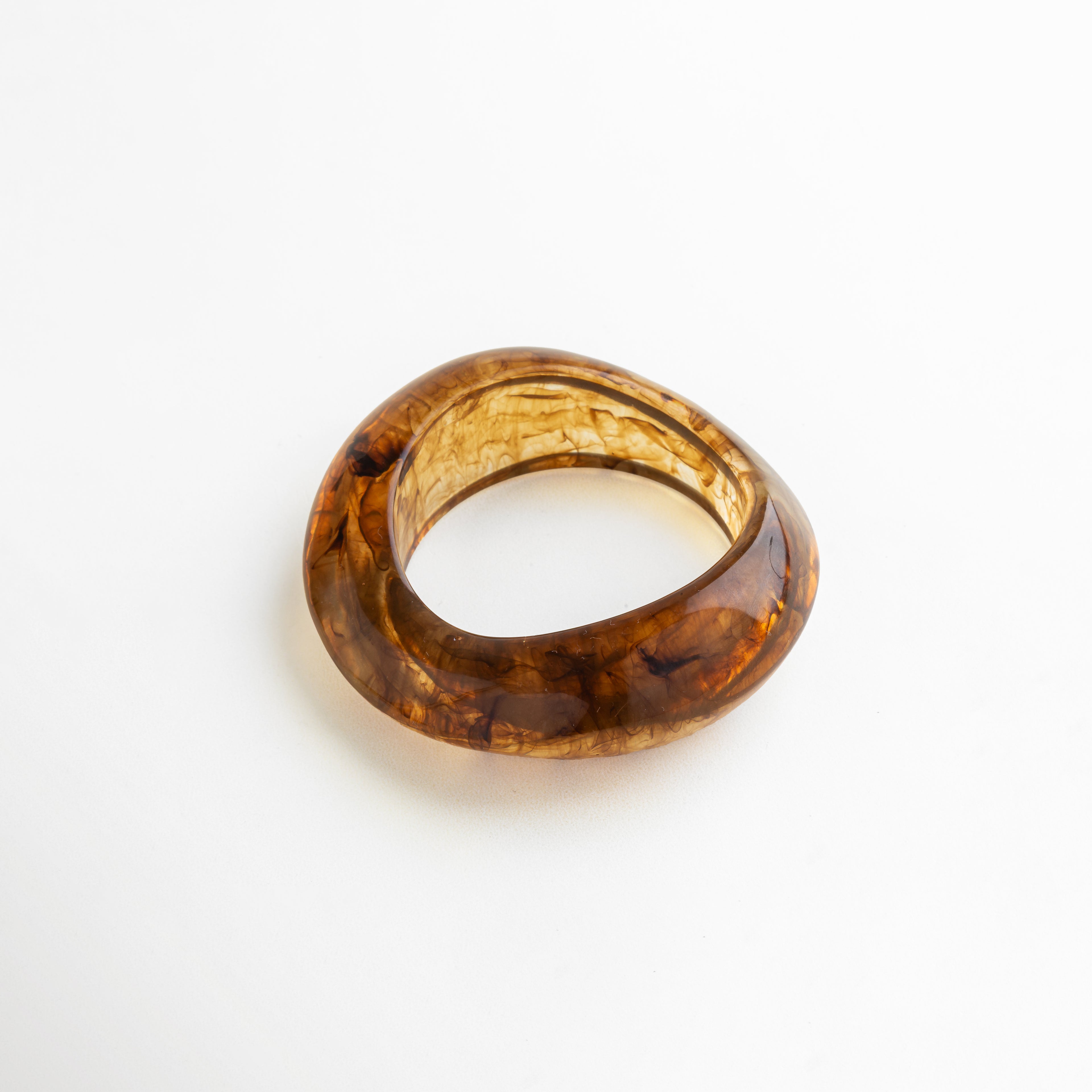 Pulsera escultural de resina ámbar con acabado marmoleado, diseño orgánico y voluminoso que aporta estilo distintivo y atemporal.