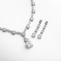 Vista del set de collar y aretes con zirconias transparentes, donde el reflejo del metal plateado resalta el resplandor cristalino de cada piedra. La composición combina elegancia moderna con un aire clásico que complementa cualquier look formal.