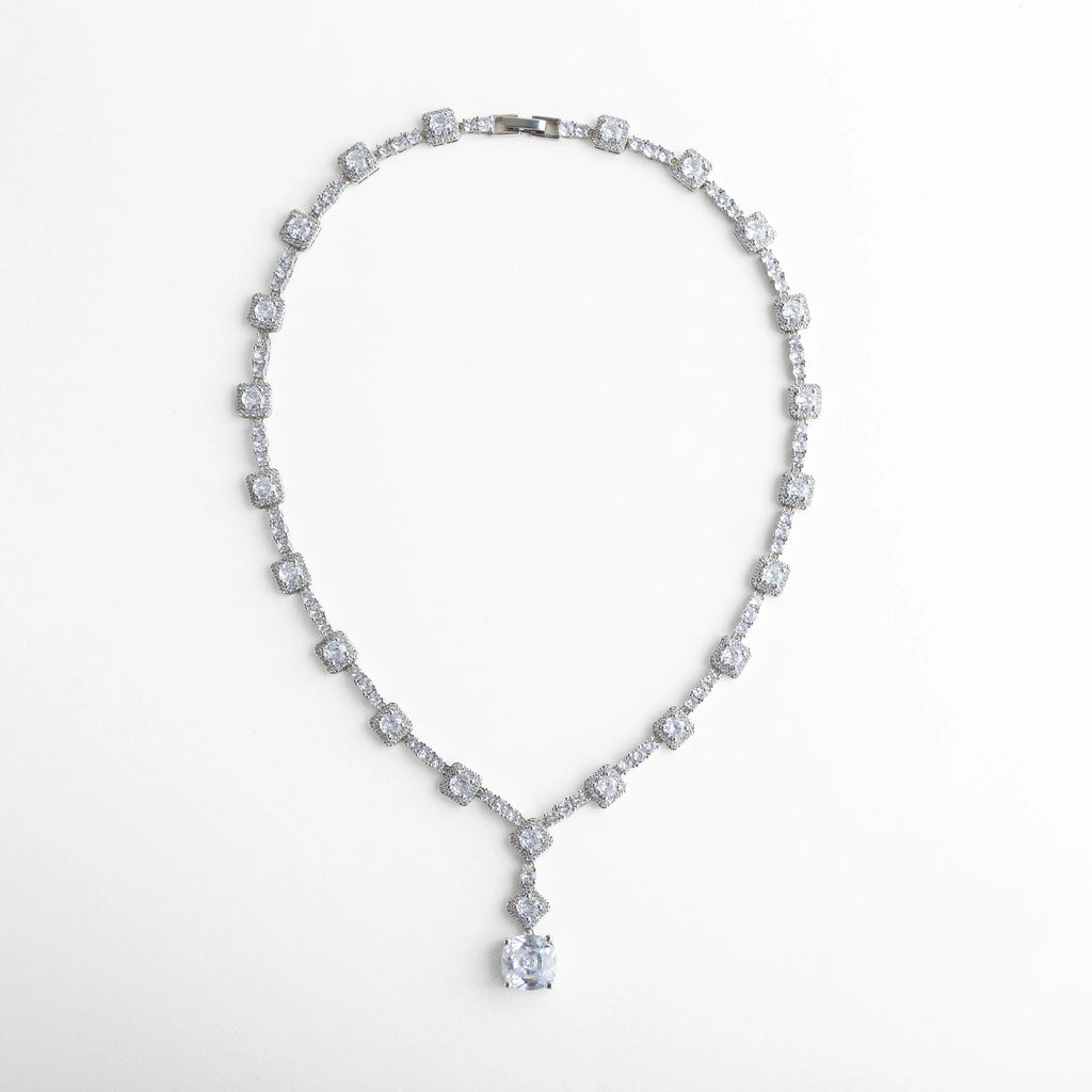 Collar plateado con diseño de zirconias cuadradas y redondas intercaladas, formando un patrón continuo de luz y brillo. Su estructura flexible y caída natural enmarca el cuello con un acabado impecable y un destello glamuroso.