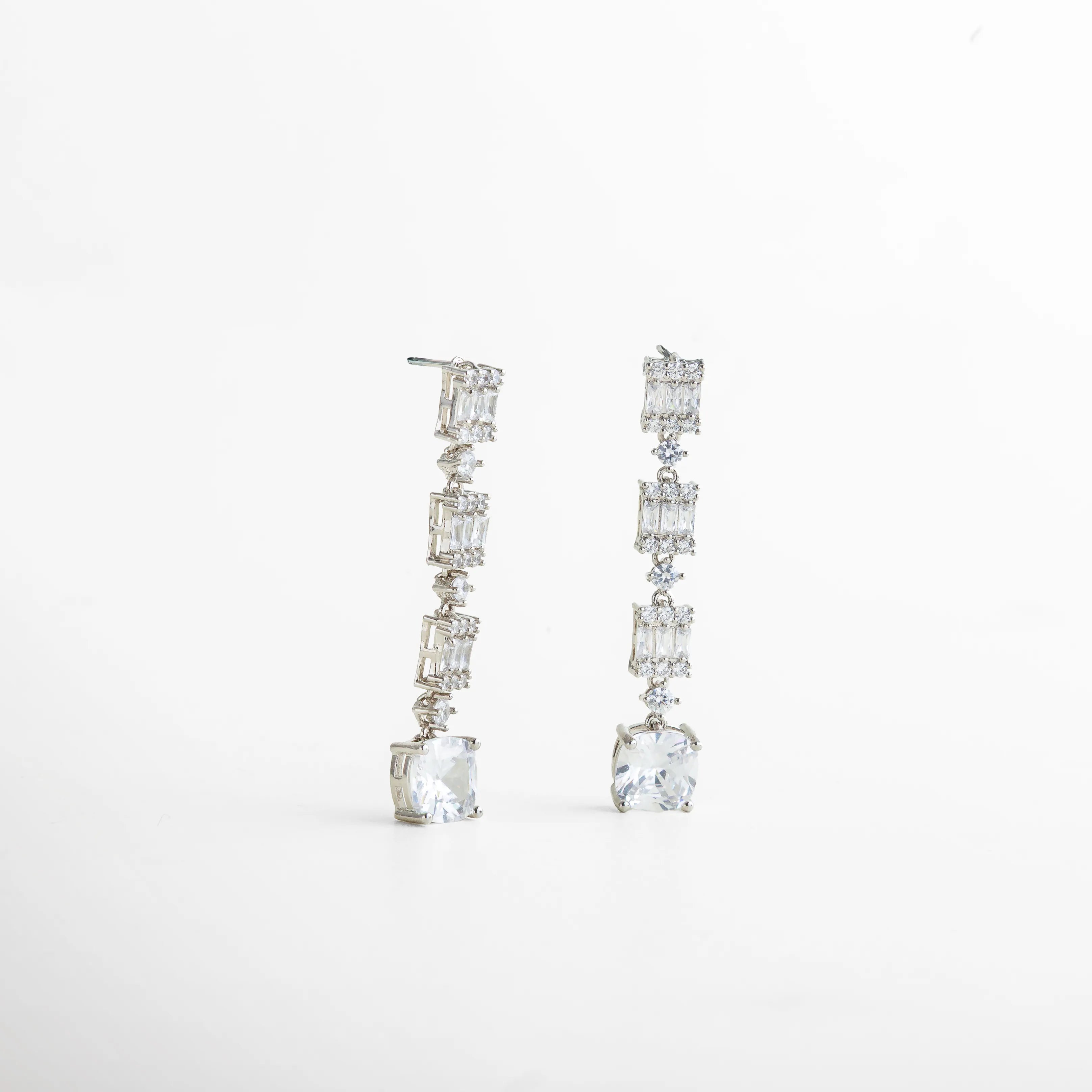 Vista lateral de los aretes plateados con zirconias engastadas, mostrando su estructura ligera y acabado pulido. Reflejan sofisticación y elegancia, ideales para combinar con el collar del set o llevar como pieza independiente.