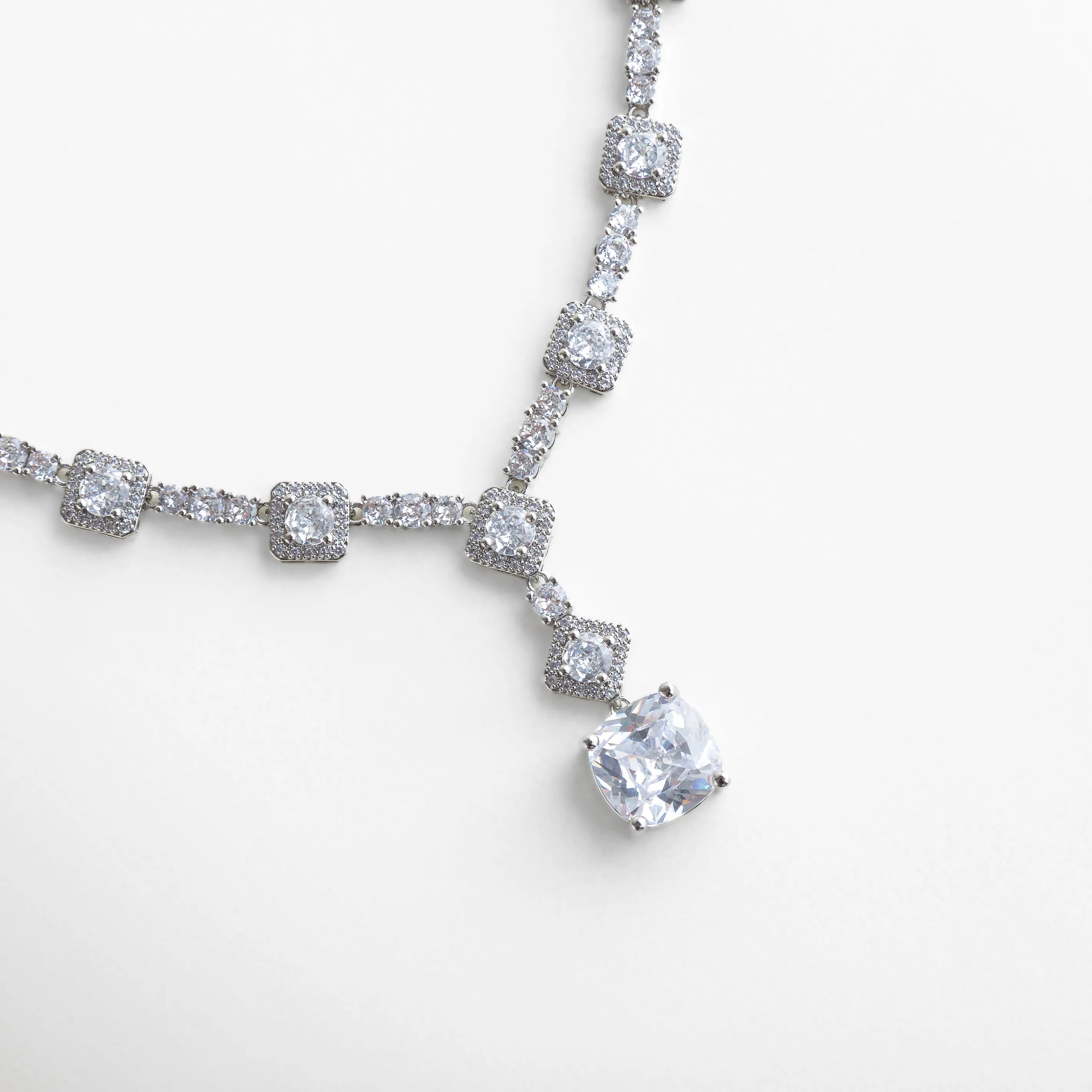 Collar plateado con incrustaciones de zirconias brillantes, diseñado con eslabones geométricos que enmarcan un colgante central de piedra facetada. Su brillo intenso y disposición simétrica evocan lujo y sofisticación, ideal para ocasiones elegantes o eventos de noche.