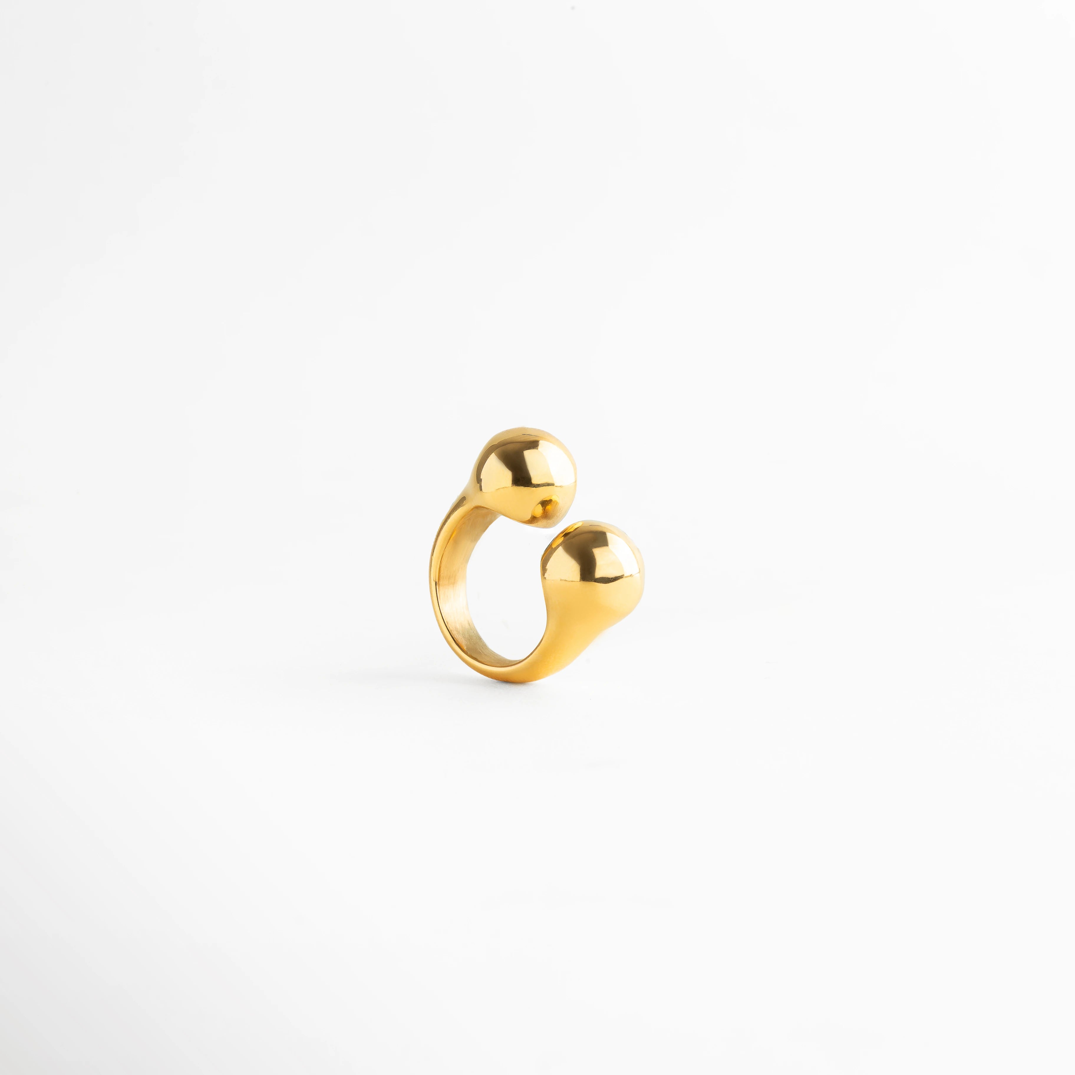 Anillo dorado contemporáneo con dos esferas redondeadas, diseño escultórico de líneas suaves y elegante acabado metálico.