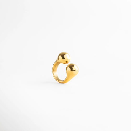 Anillo dorado contemporáneo con dos esferas redondeadas, diseño escultórico de líneas suaves y elegante acabado metálico.
