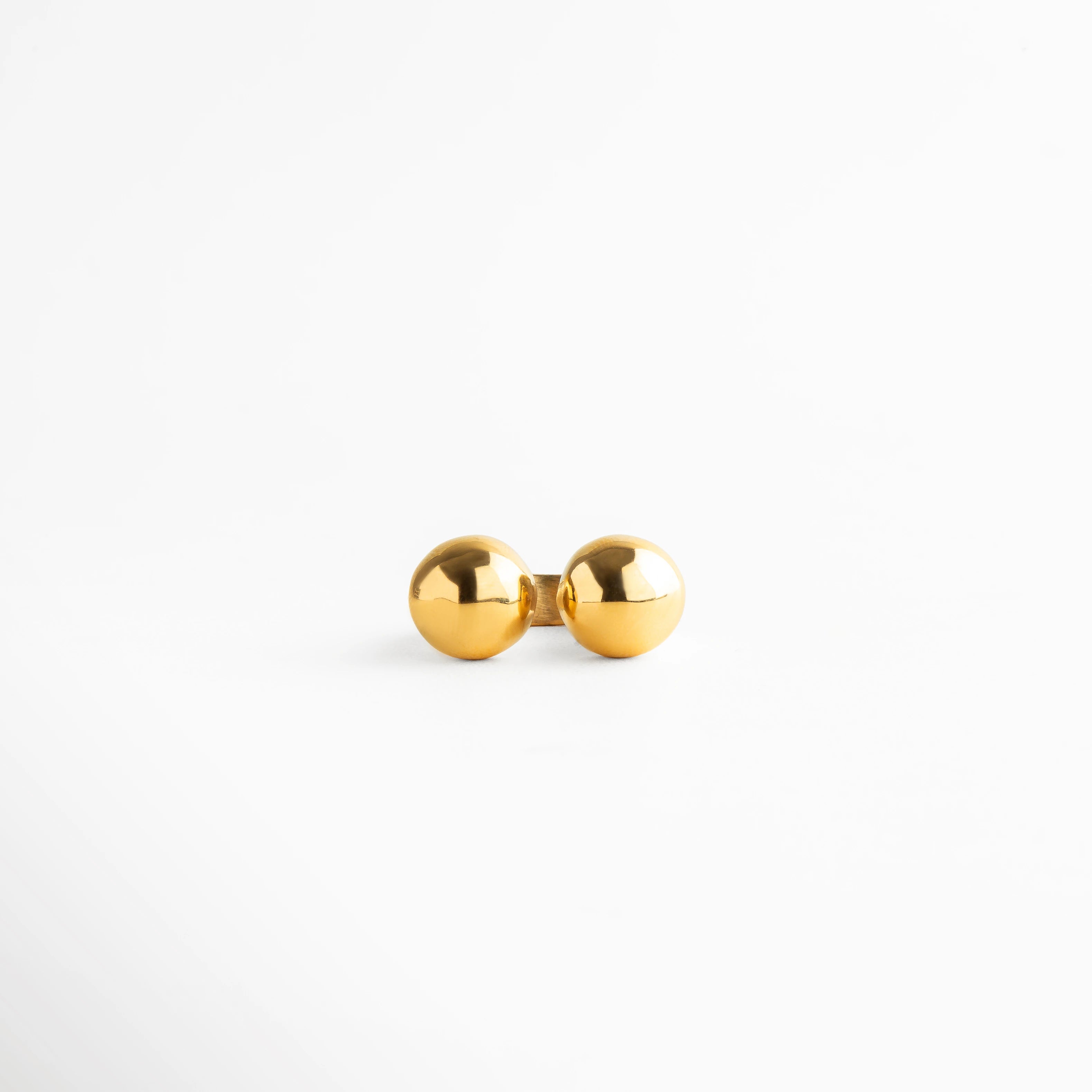 Anillo dorado con doble esfera brillante, joya moderna de diseño abierto con efecto espejo y estilo minimalista.