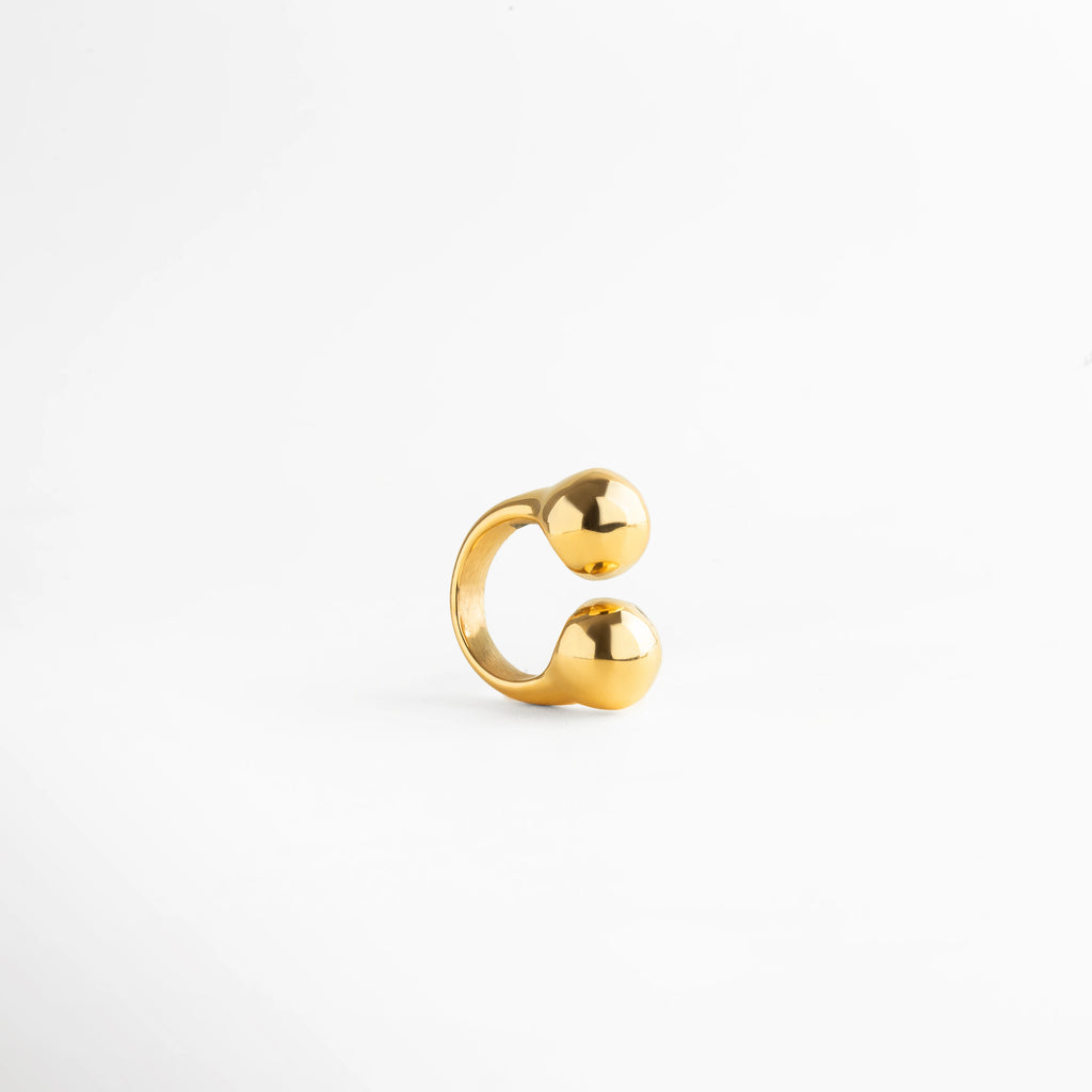 Anillo dorado abierto con diseño de doble esfera pulida, acabado brillante y estilo minimalista moderno.