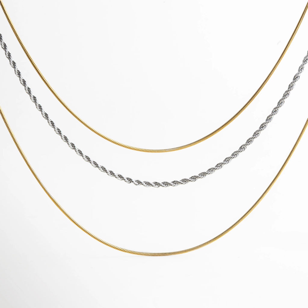 Collar de tres capas en combinación dorada y plateada, con cadenas tipo serpiente y trenza, ideal para un look moderno y elegante.