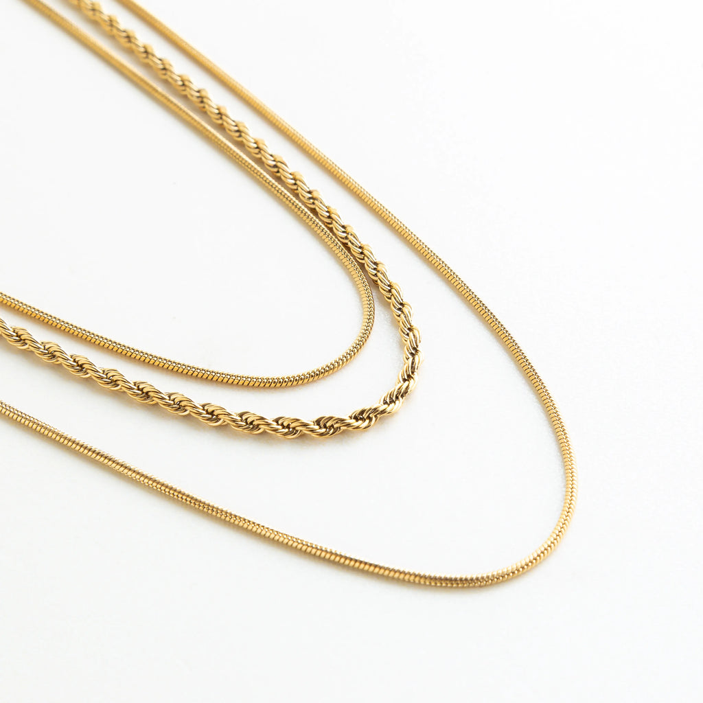 Detalle del collar dorado de capas con diferentes cadenas que aportan textura y elegancia.