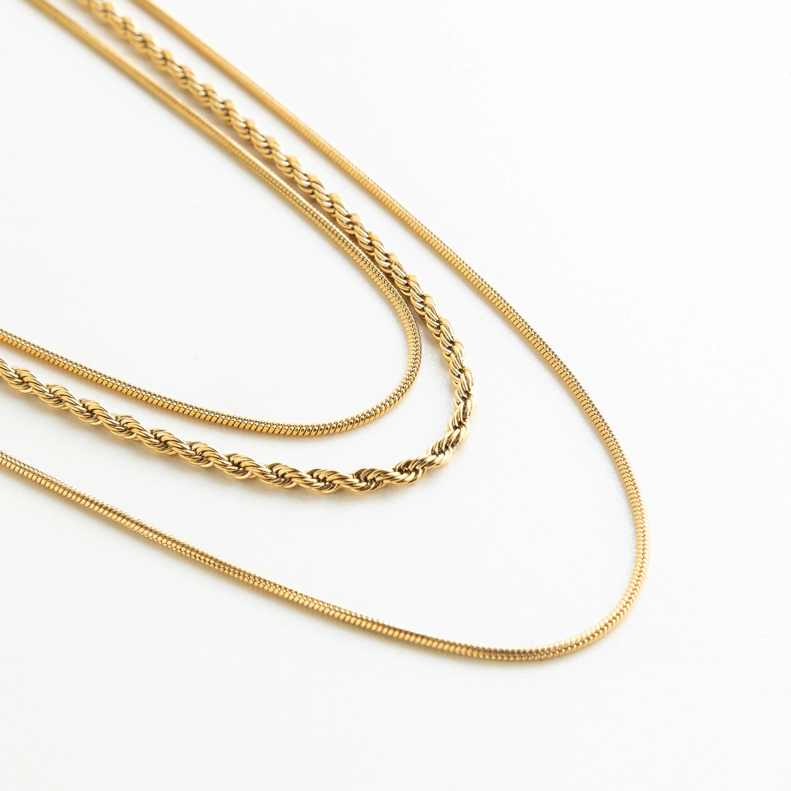 Detalle del collar dorado de capas con diferentes cadenas que aportan textura y elegancia.