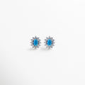 Aretes de cobre con recubrimiento en plata esterlina, incrustaciones de zirconias cúbicas transparentes rodeando piedra central azul en forma ovalada, diseño clásico y elegante de 1.8 cm de largo por 1.3 cm de ancho, joya femenina sofisticada.