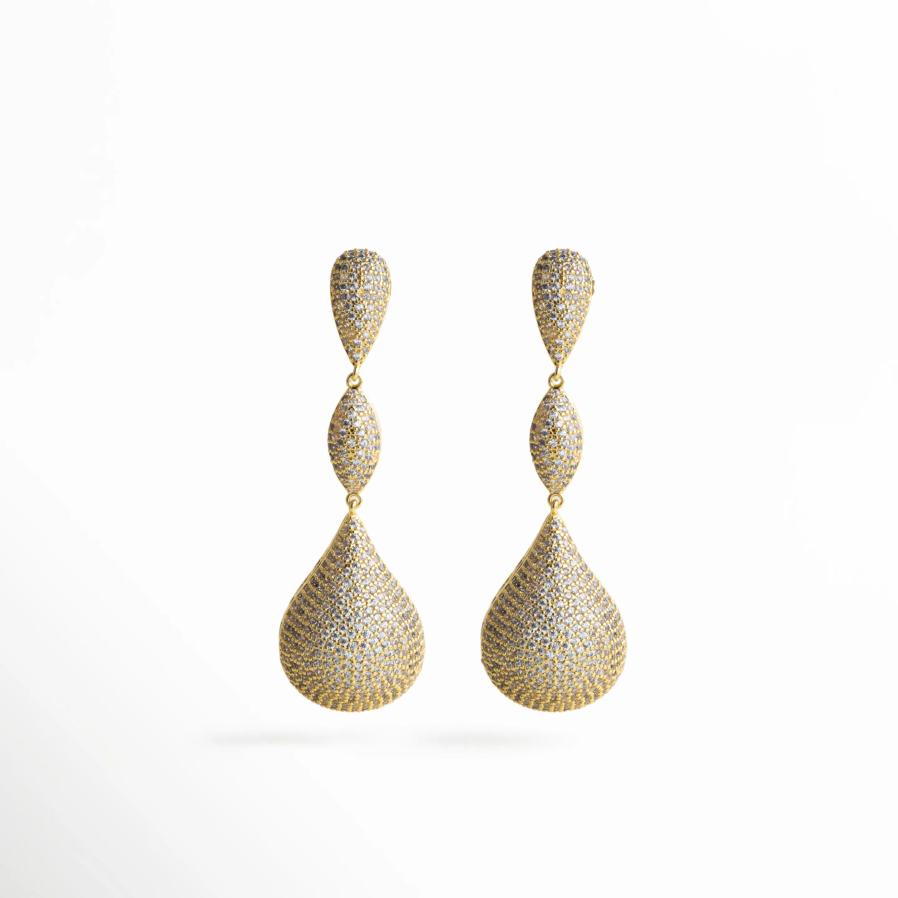 Aretes dorados largos con zirconias incrustadas, diseño elegante en forma de gota triple que refleja brillo y sofisticación.