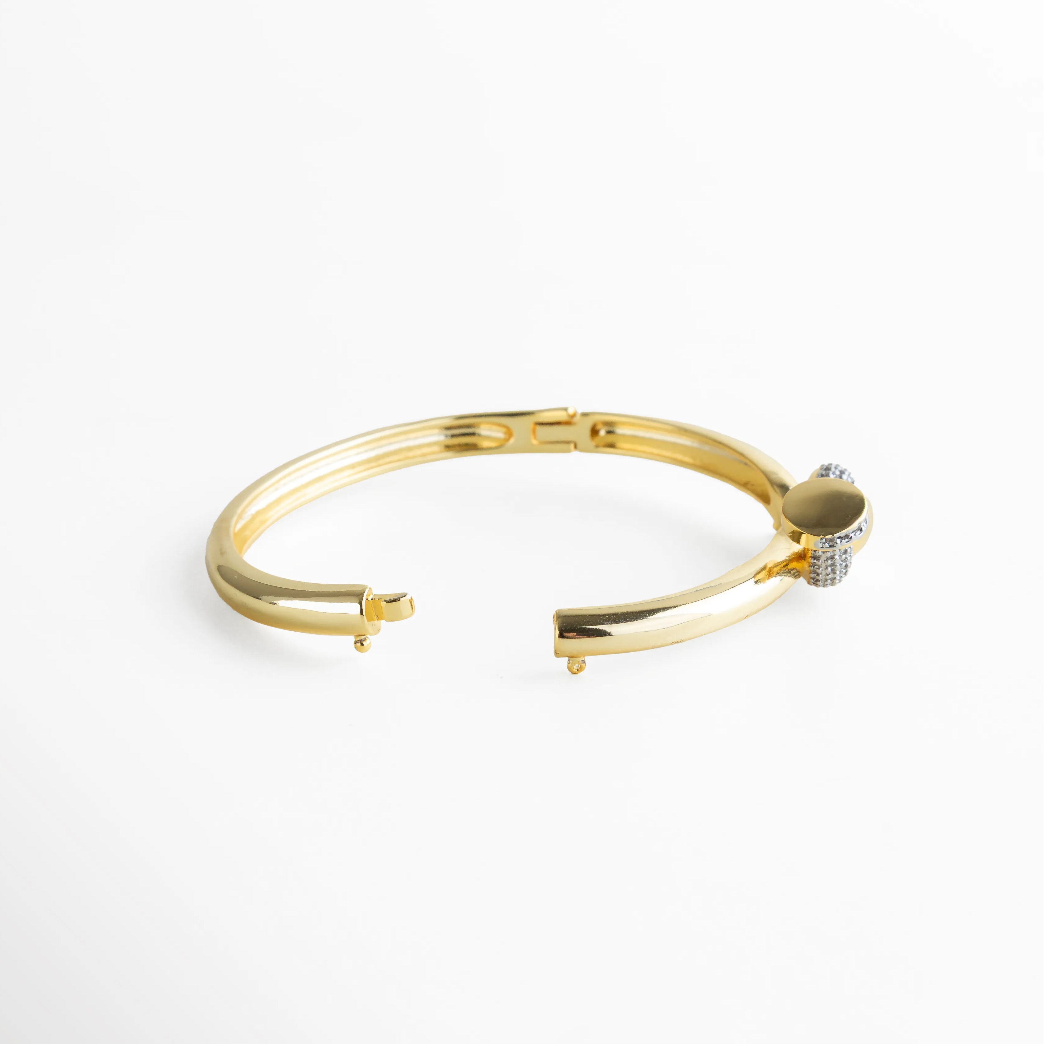 Pulsera rígida dorada con sistema de apertura invisible y broche seguro, destacando su estructura sólida y el diseño fluido del nudo. La toma enfatiza su practicidad sin perder la esencia lujosa de la pieza, perfecta para uso diario o eventos especiales.