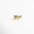 Anillo dorado con nudo central y brazos entrelazados con incrustaciones brillantes.
