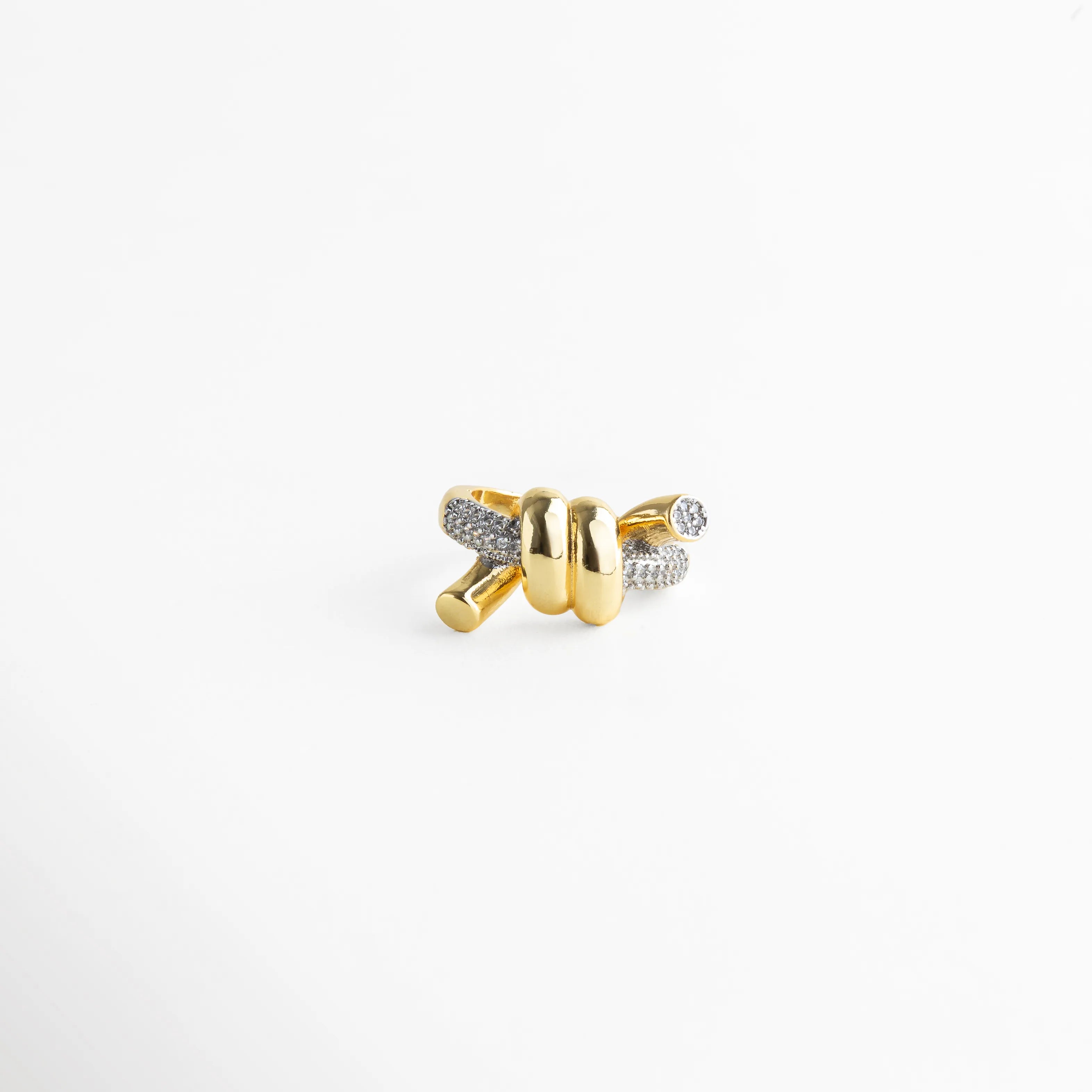 Anillo dorado con nudo central y brazos entrelazados con incrustaciones brillantes.