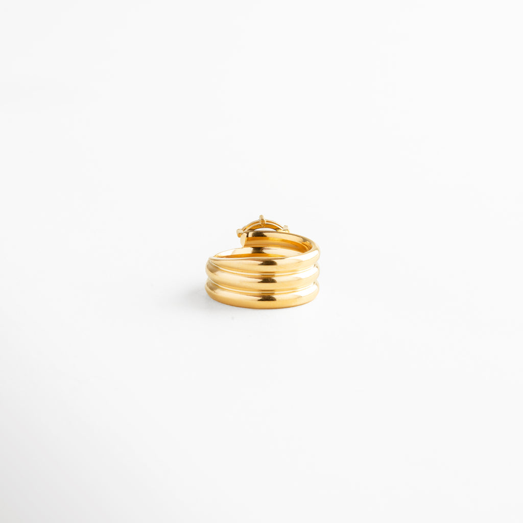 Vista lateral de anillo triple aro dorado con zirconia marquise engastada en oro 18K