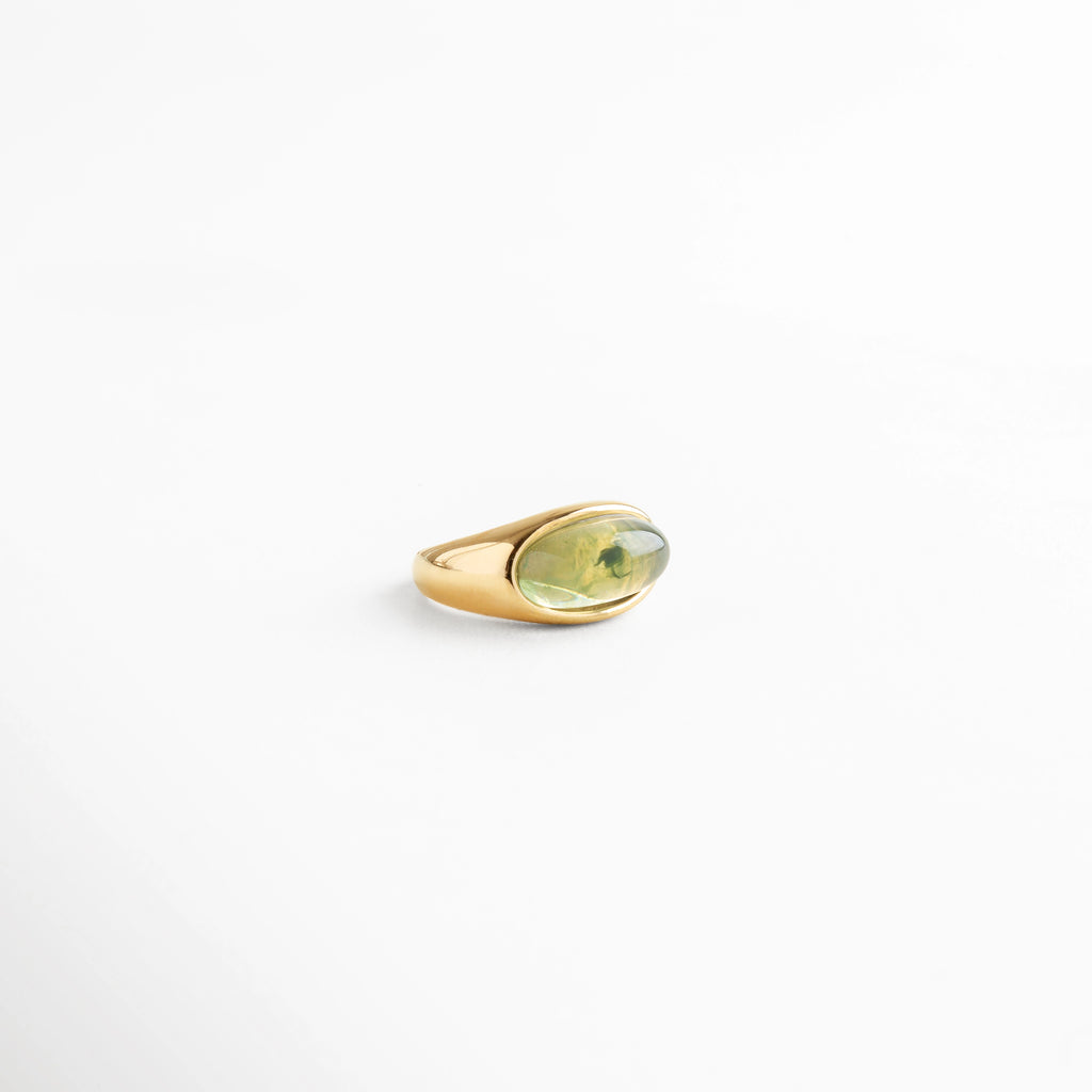 Anillo dorado con piedra verde ovalada en resina, diseño versátil y elegante, ideal como accesorio statement.