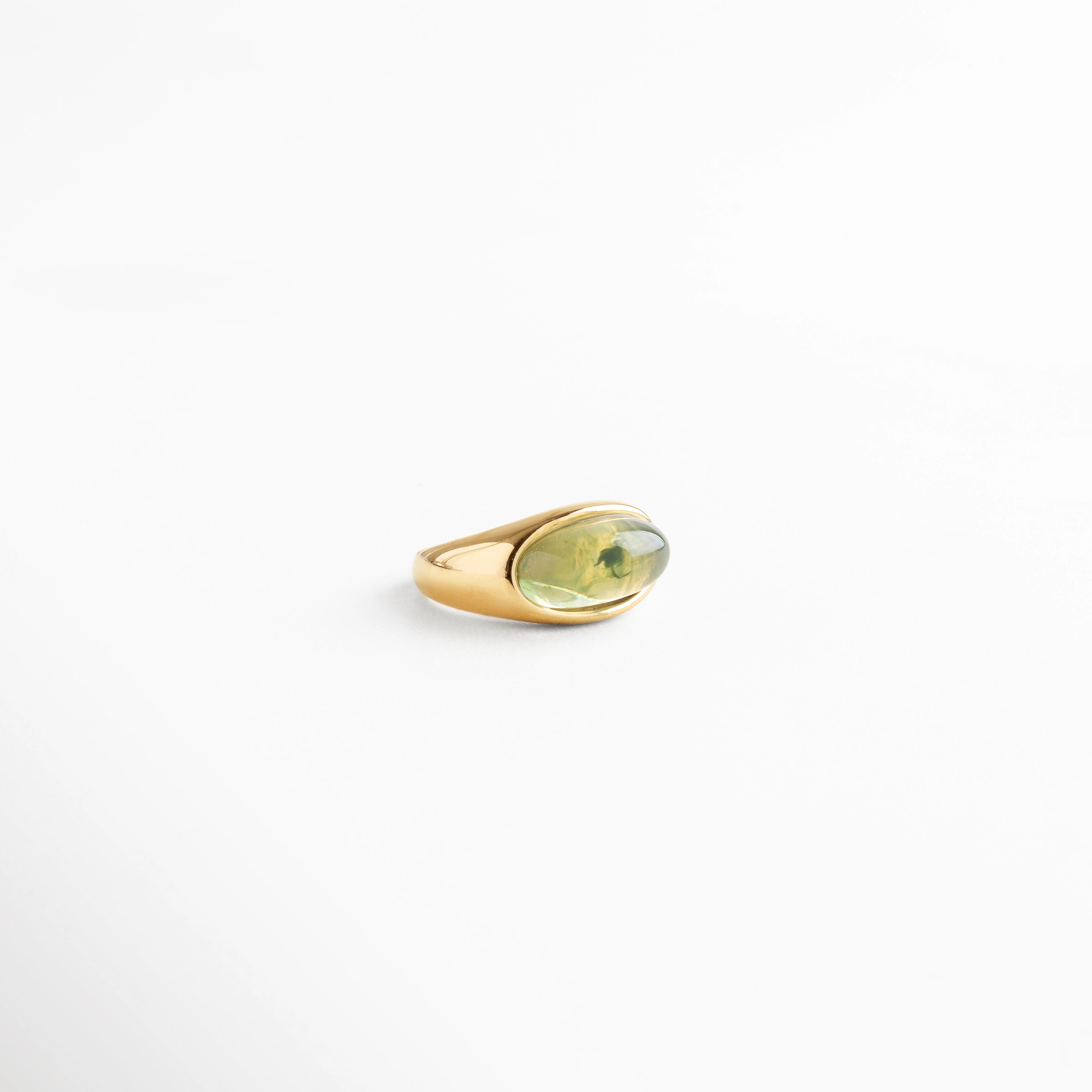 Anillo dorado con piedra verde ovalada en resina, diseño versátil y elegante, ideal como accesorio statement.